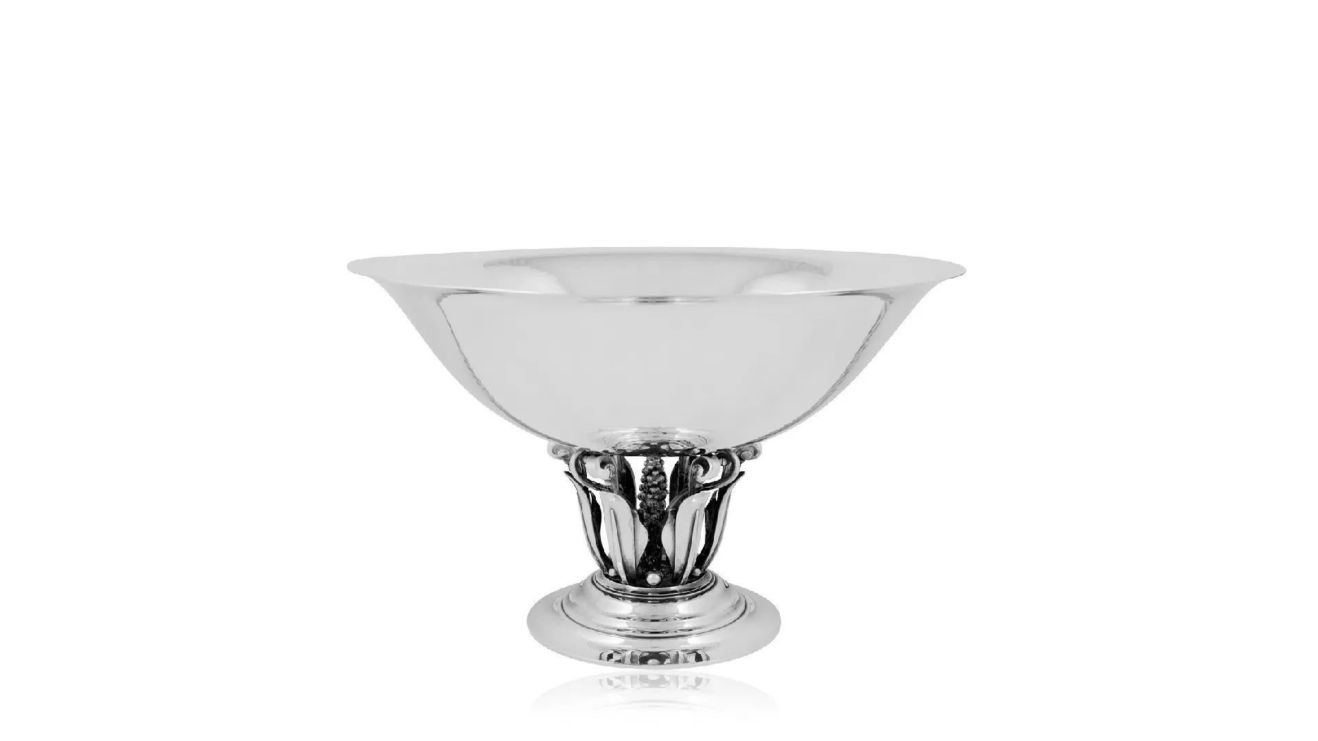 A sterling silver Georg Jensen bowl, featuring a pierced stem adorned with floral details and scrolls. It was designed by Johan Rohde in 1919, identified by design number #242. The bowl sits atop a round raised tiered base connected to a central