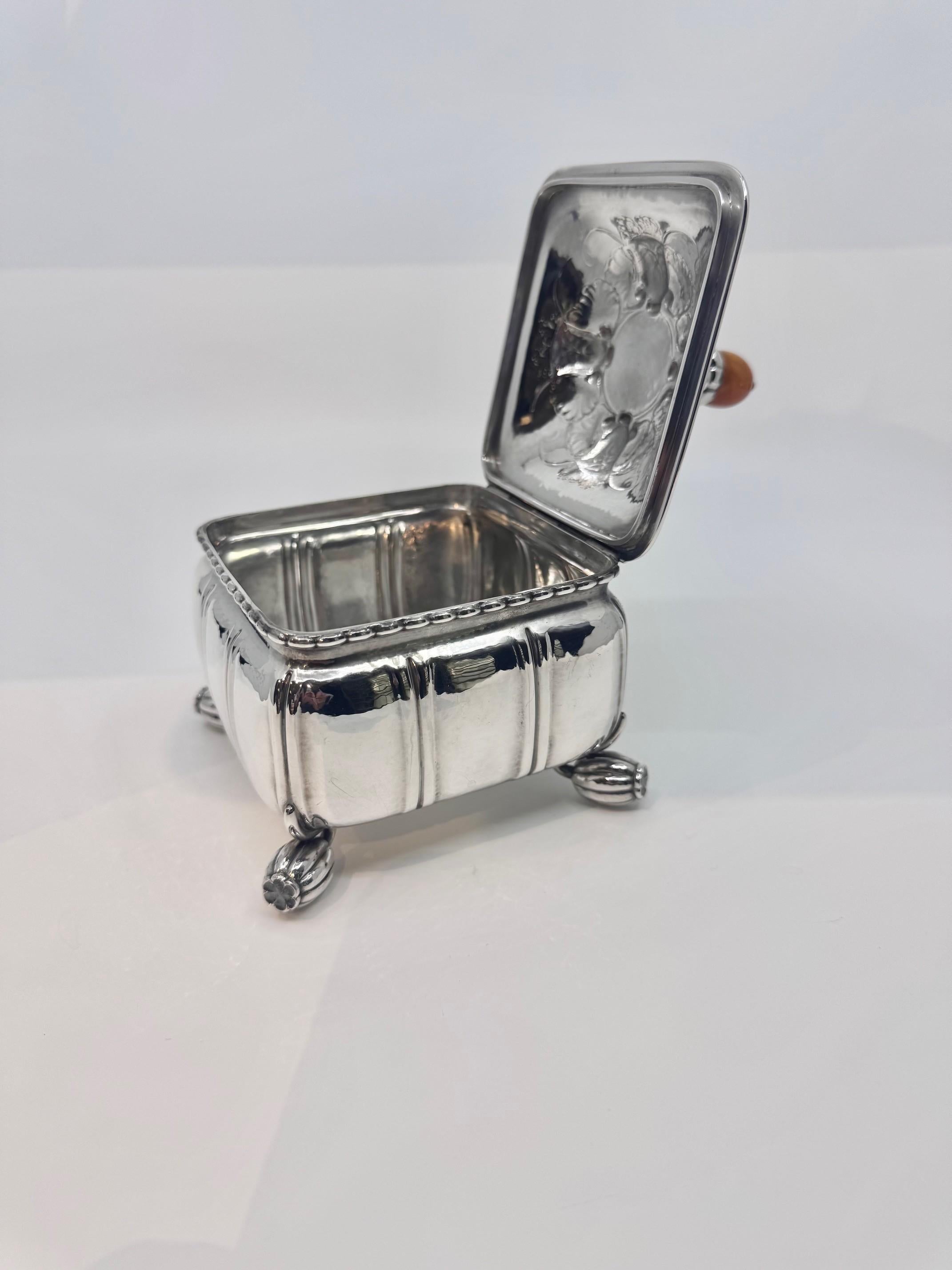 A Vintage Sterling Silver Georg Jensen Box with Amber Agate Finial, Design #30, designed by Georg Jensen in 1913.

This exquisite sterling silver box by renowned silversmith Georg Jensen showcases exceptional craftsmanship. The amber agate finial is