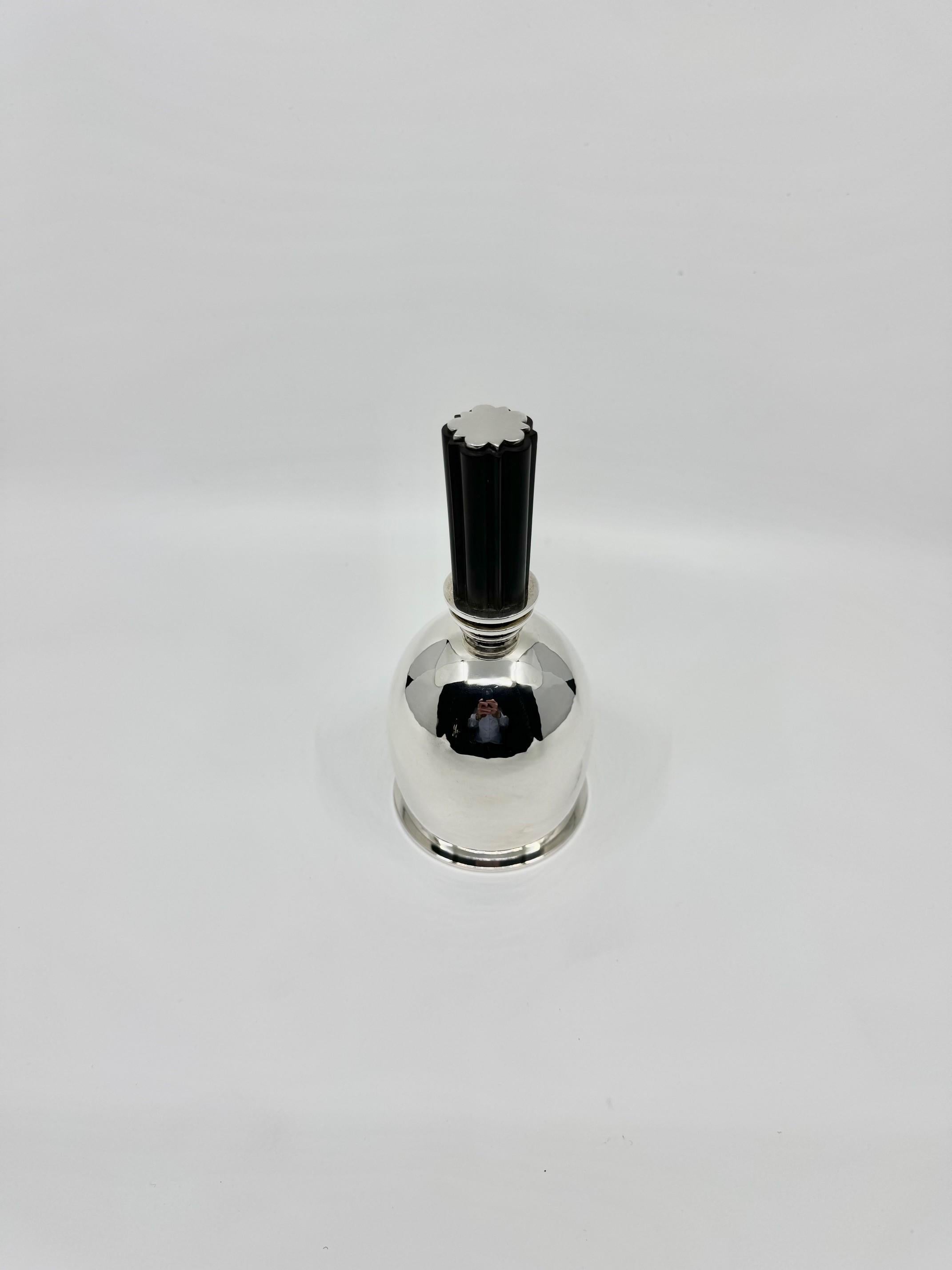 An Art Deco sterling silver chairman's bell with an ebony handle, design #729 by Harald Nielsen, circa 1934. This bell features an extra-large, domed design, notable for its unusually thick and heavy quality. The base consists of a ring attached to