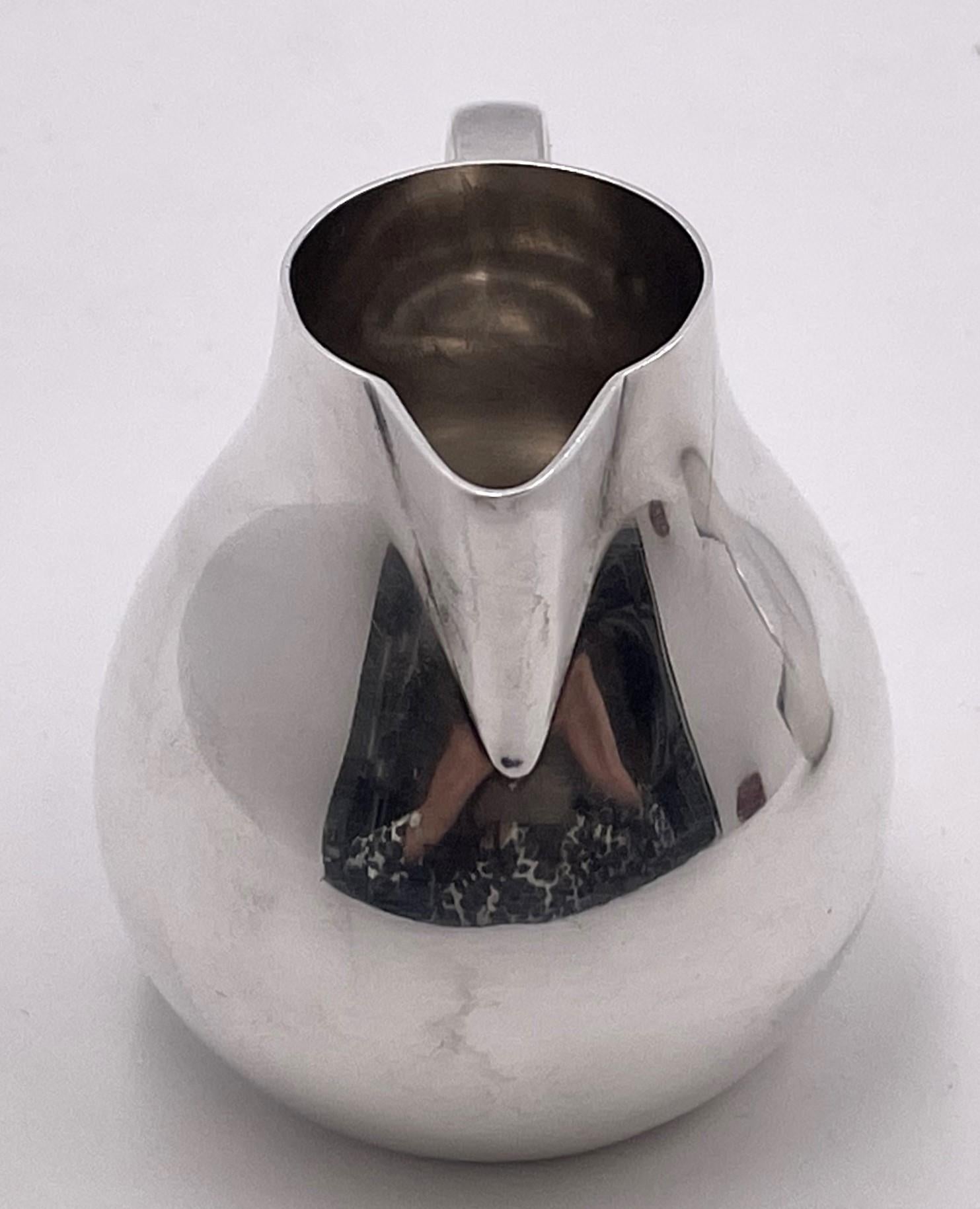 Set of Georg Jensen by Sigvard Bernadotte creamer and covered sugar bowl in Bernadotte pattern number 1015 in Mid-Century Modern style, with an elegant, geometric design, from the mid-20th century. The creamer measures 2 3/4'' in height by 2 7/8''