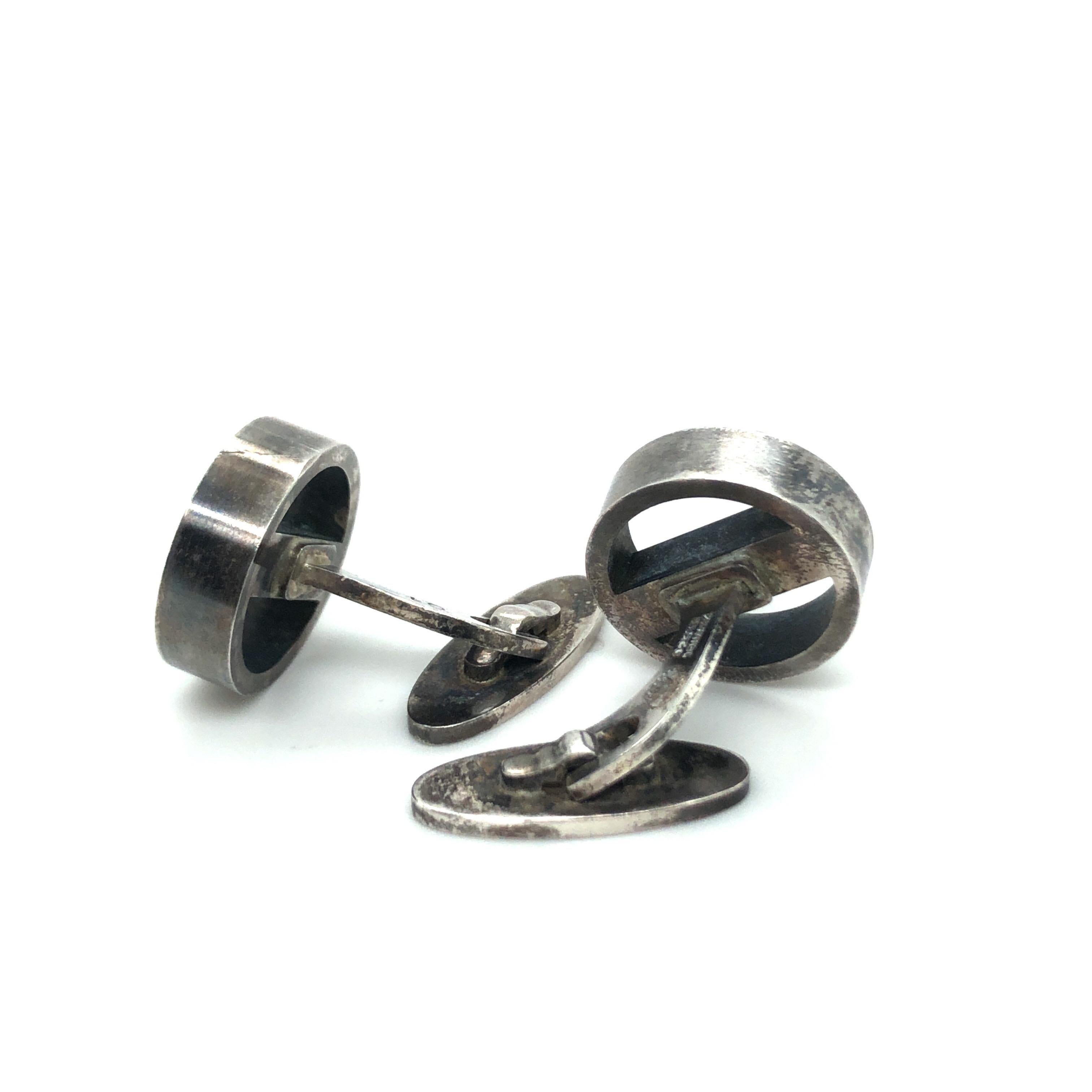 Sterling Silver Cufflinks No. 91 by Georg Jensen.

Stylish whale back cufflinks crafted in 925 Sterling Silver. The face of each cufflink is designed as a wheel crossed by a bar. 
They are in good vintage condition with a wonderful patina which