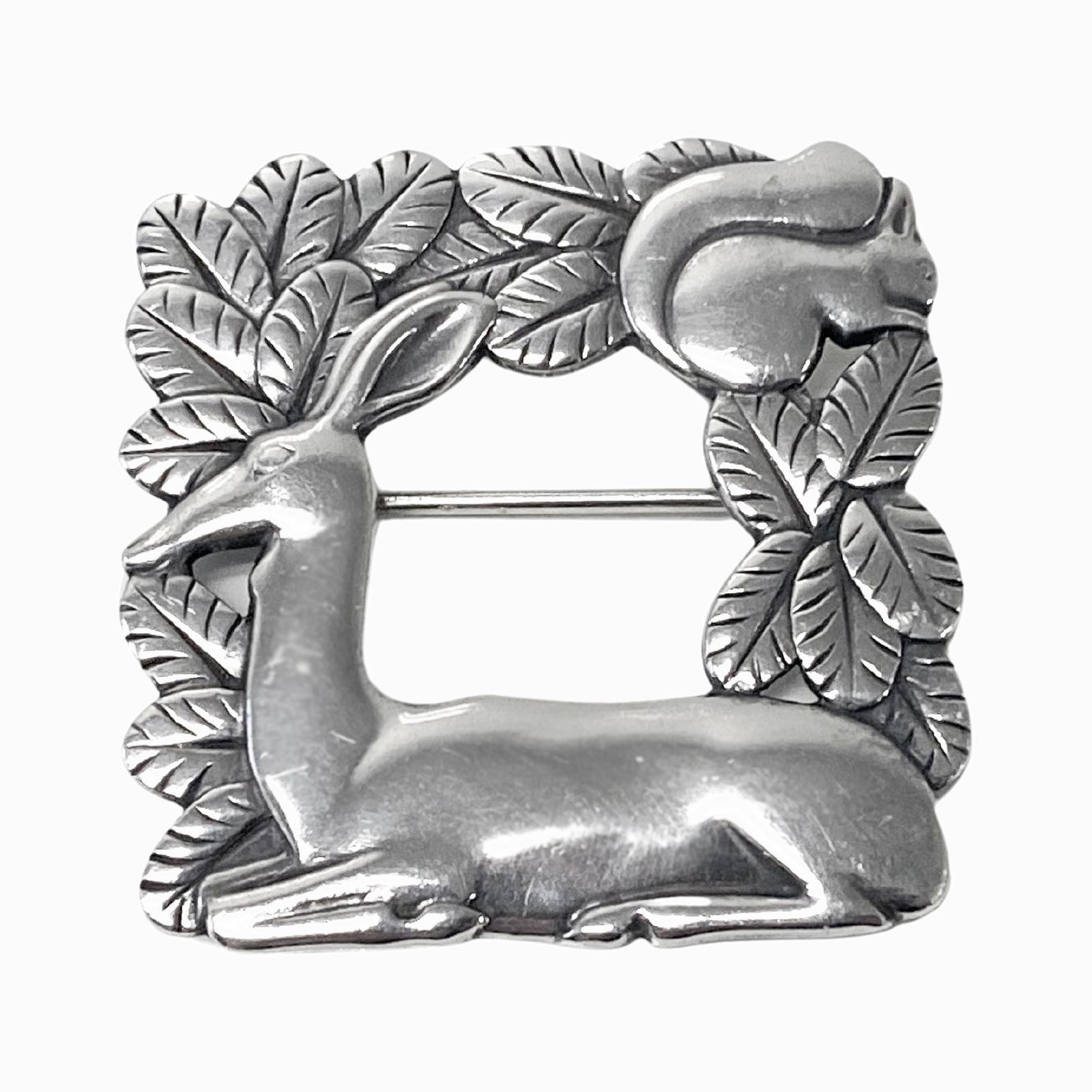 Georg Jensen Sterling Silver Deer and Squirrel Brooch #318 Vintage Sterling Silver, designed by Arno Malinowski. Intricately detailed, open-squared brooch featuring a deer resting with squirrel in foliage. Measures: 1.5 x 1.5 inches. Item Weight: