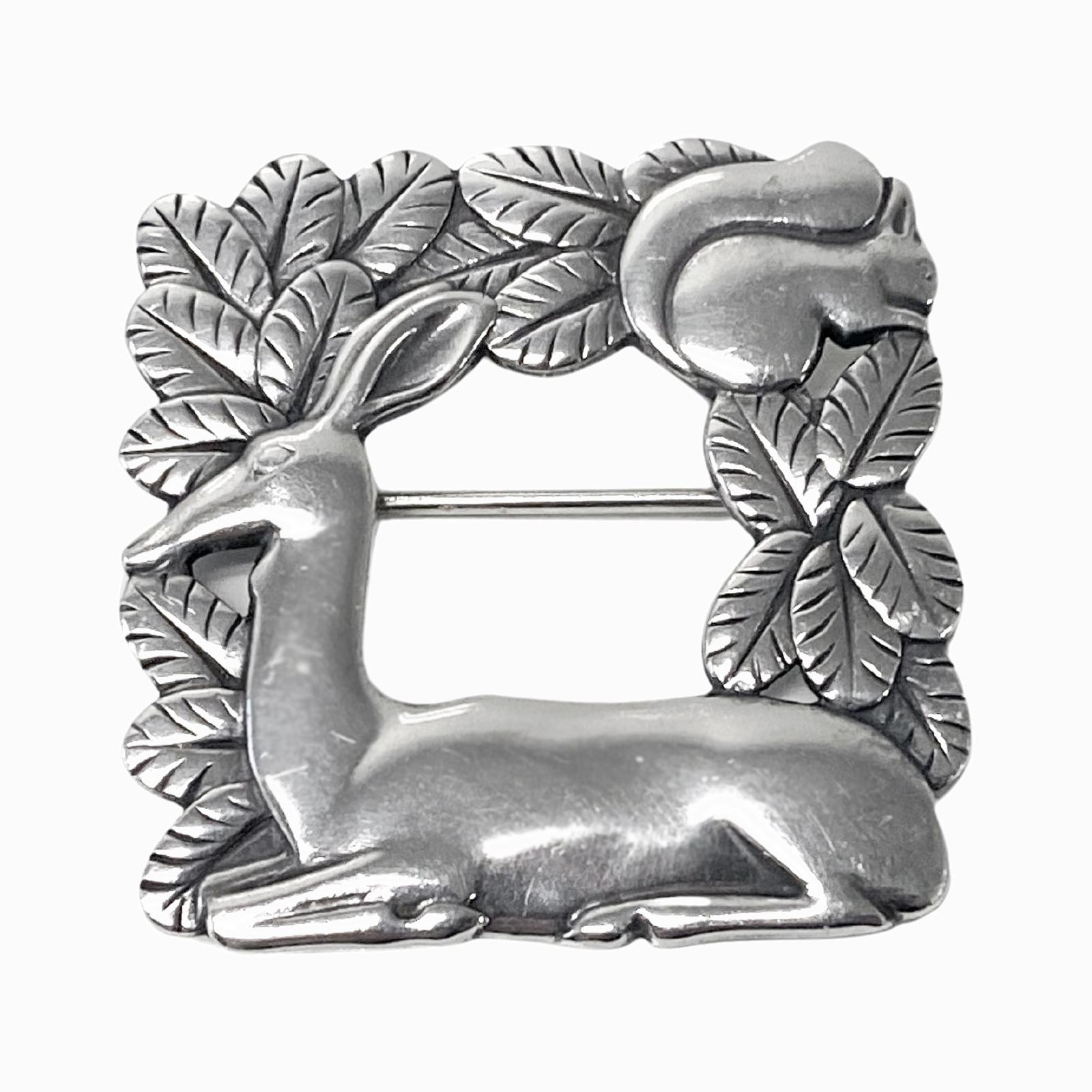 Georg Jensen Sterling Silver Broche cerf et écureuil #318 Vintage Sterling Silver, conçu par Arno Malinowski. Broche en forme d'équerre ouverte, aux détails complexes, représentant un cerf se reposant avec un écureuil dans le feuillage. Mesures :