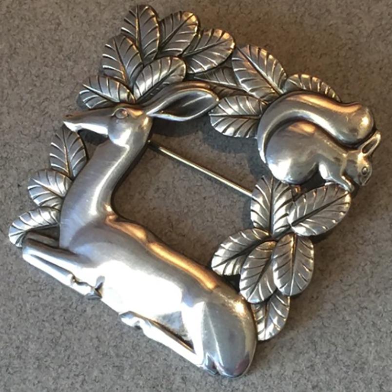 Georg Jensen Sterling Silver Deer and Squirrel Brooch No. 318 by Arno Malinowski.

 

Intricately detailed, open-squared brooch featuring a deer resting before a squirrel in foliage. Very well made with gorgeous patina and secure clasp.

English