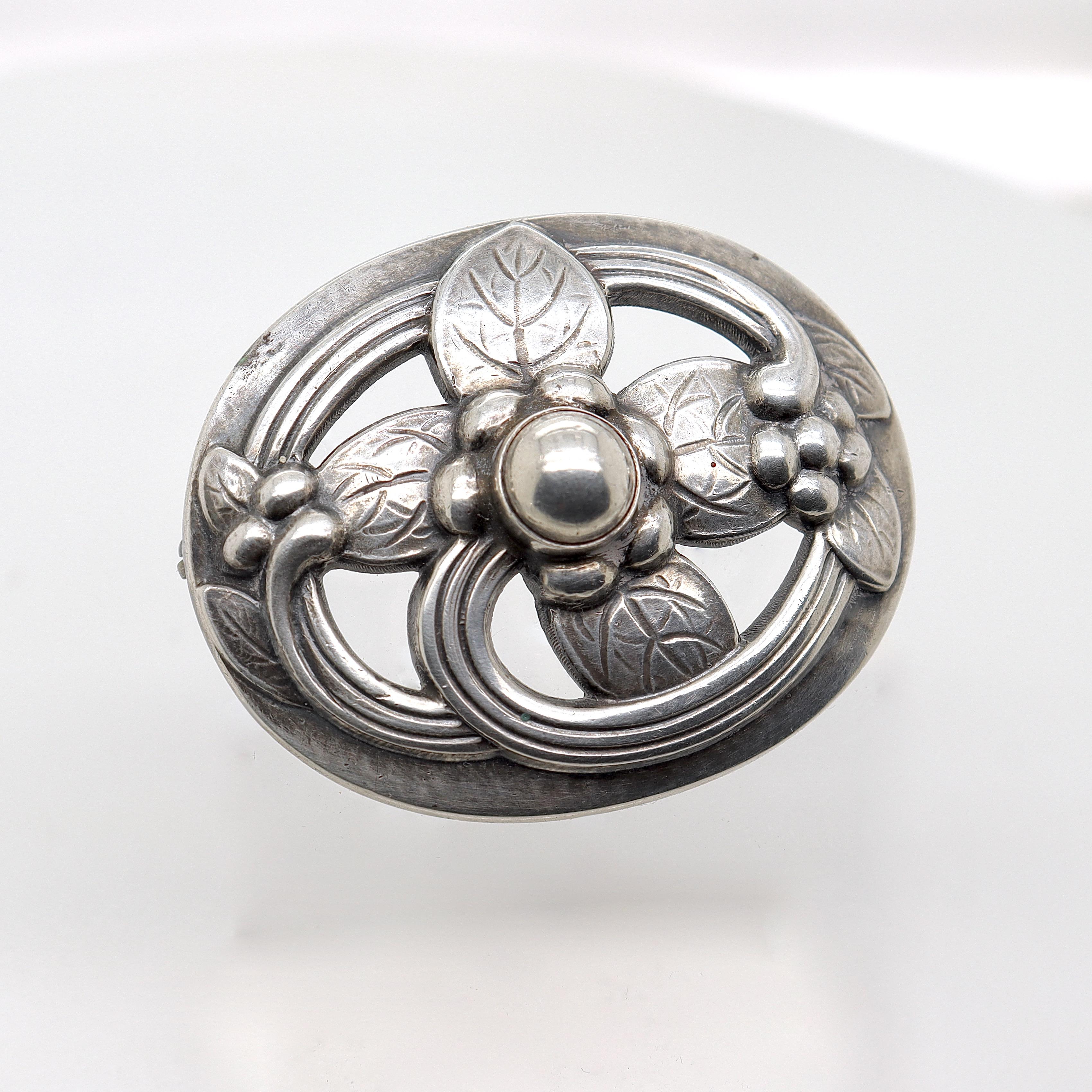 A fine Georg Jensen sterling silver pin or brooch.

Model no. 138.

Designed by Georg Jensen.

In the form of a hand-hammered, stylized flower set inside an oval.

Simply a wonderful brooch from Denmark's premier silversmiths!