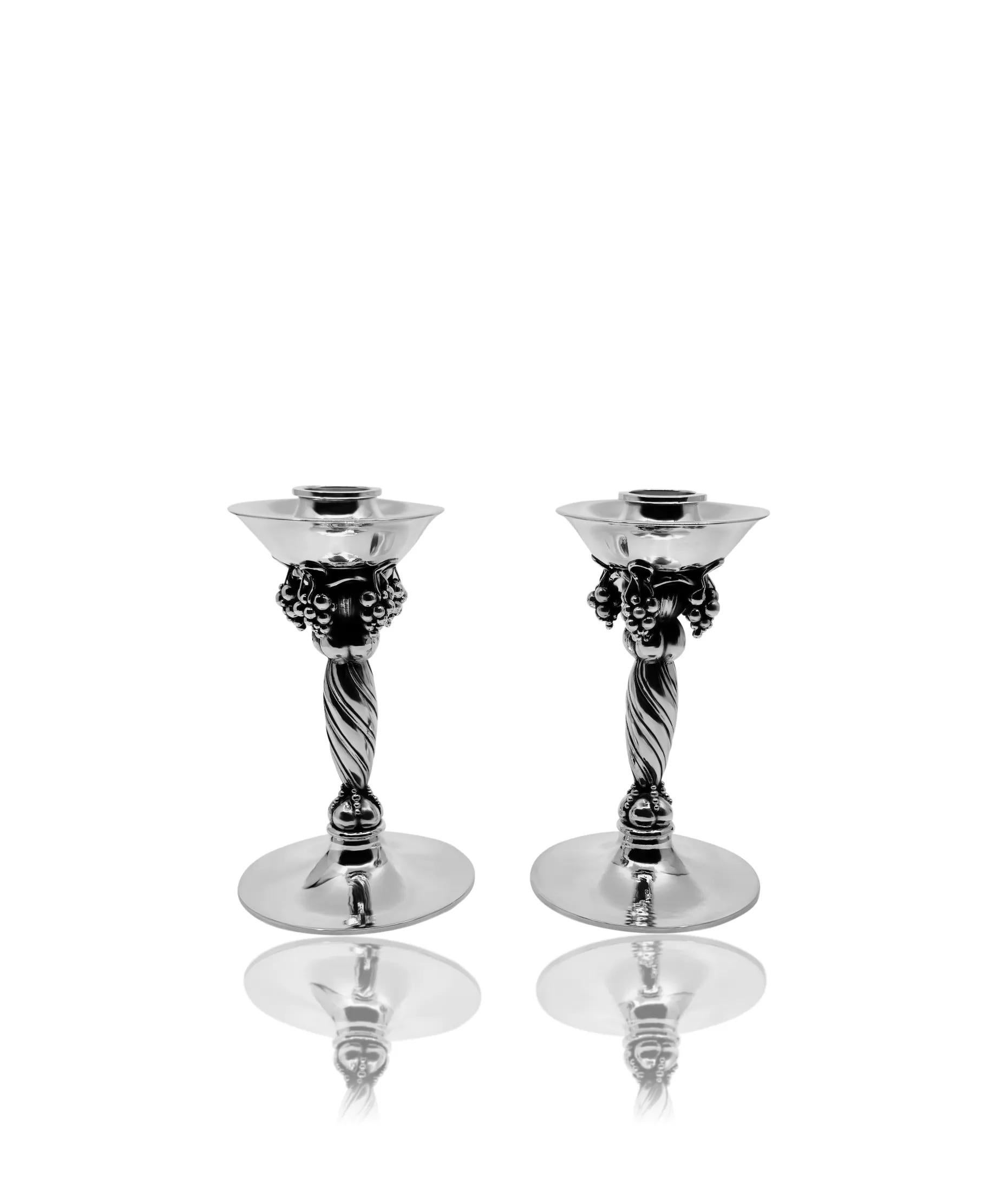 A pair of vintage Georg Jensen Grape candlesticks, design #263A by Georg Jensen from 1930. This vintage pair boasts exquisite craftsmanship, evident in the intricate hand chasing technique employed, as opposed to casting. The stem, adorned with a