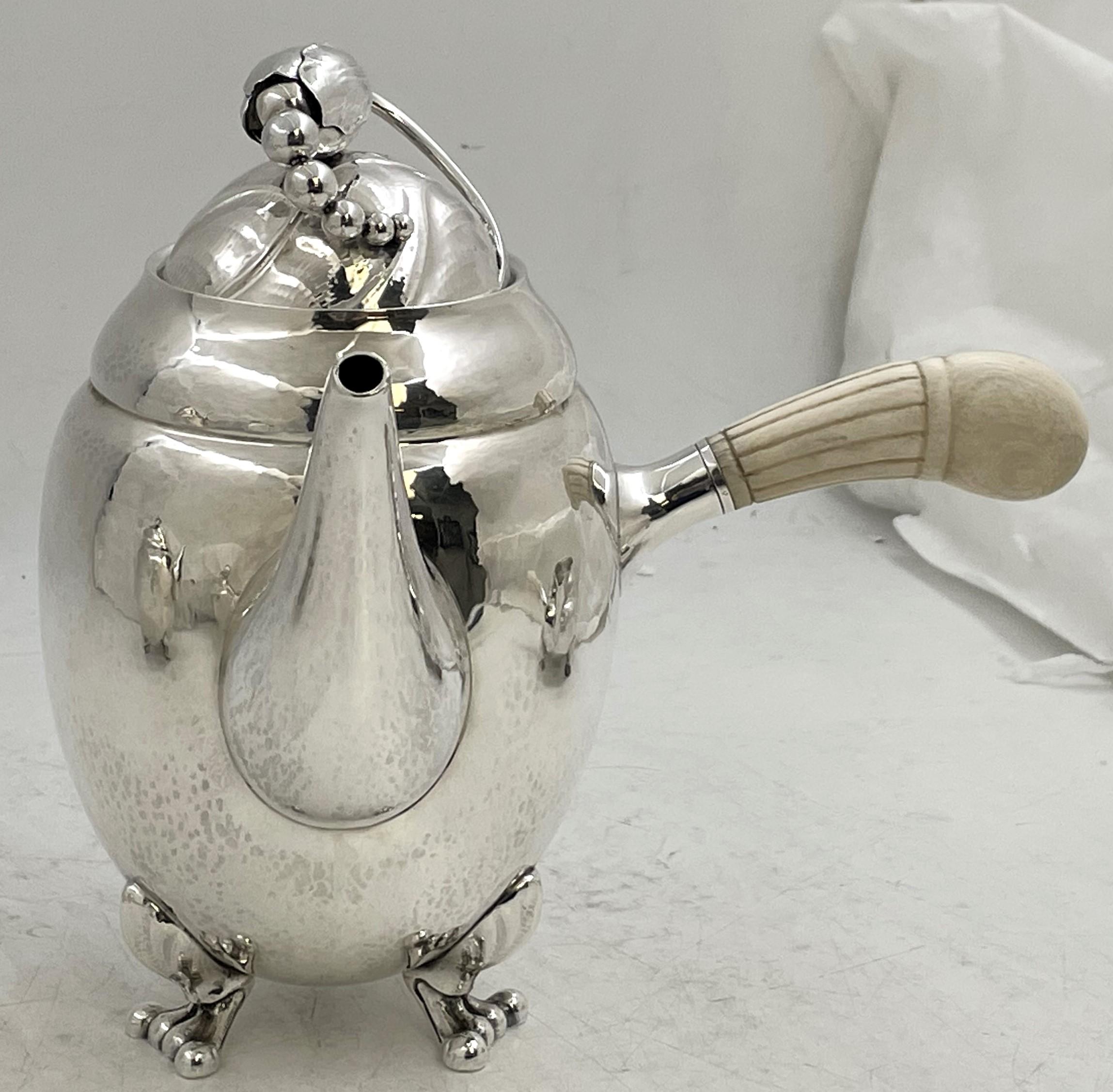 Georg Jensen sterling silver hand-hammered 5-piece tea and coffee set in the celebrated Blossom pattern and in Art Nouveau style, adorned with stylized natural and geometric motifs, consisting of: 

- a coffeepot measuring 7 7/8'' in height by 7