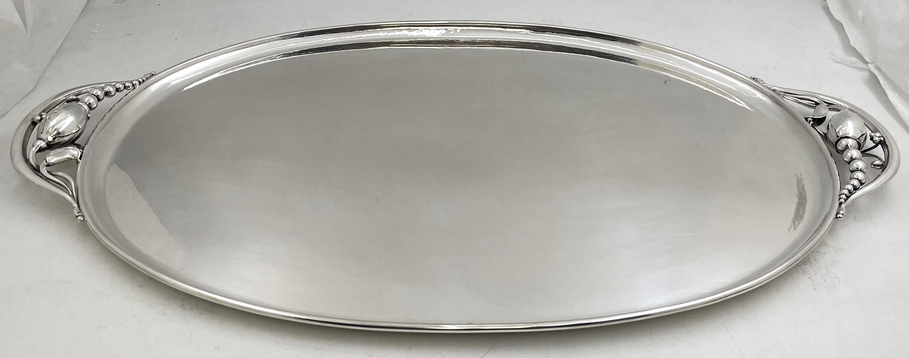 Georg Jensen sterling silver hand-hammered tray in the celebrated Blossom pattern number 2I and in Art Nouveau style, adorned with stylized natural and geometric motifs, made in the mid-20th century. It measures 23 1/2'' in length from handle to