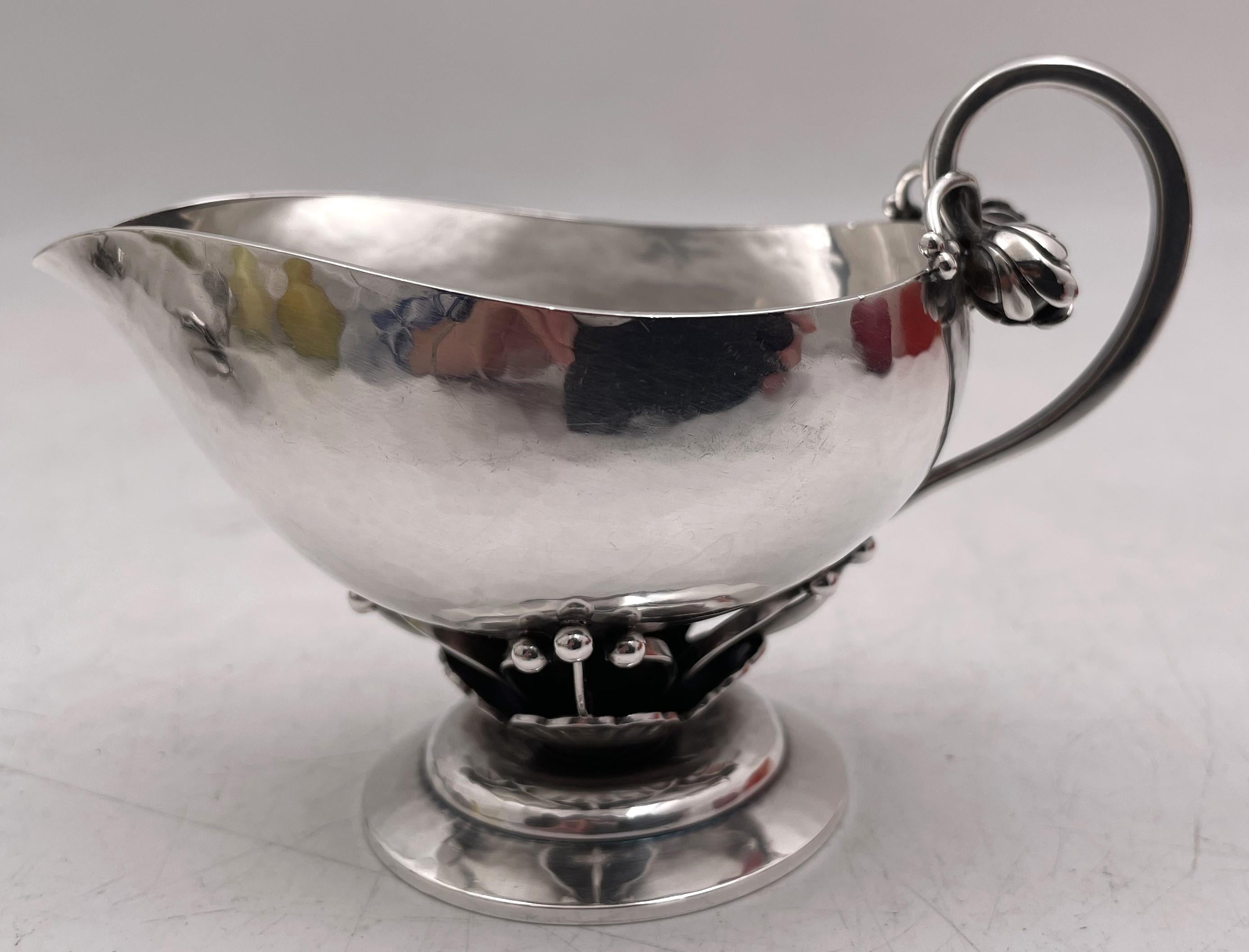 Lattiera e zuccheriera in argento sterling di Georg Jensen, entrambe con il raro motivo numero 235A, ornate da motivi naturali stilizzati e su basi ovali a gradini. La lattiera misura 2 3/4'' di altezza, 4'' dal manico al beccuccio e 2 1/8'' di