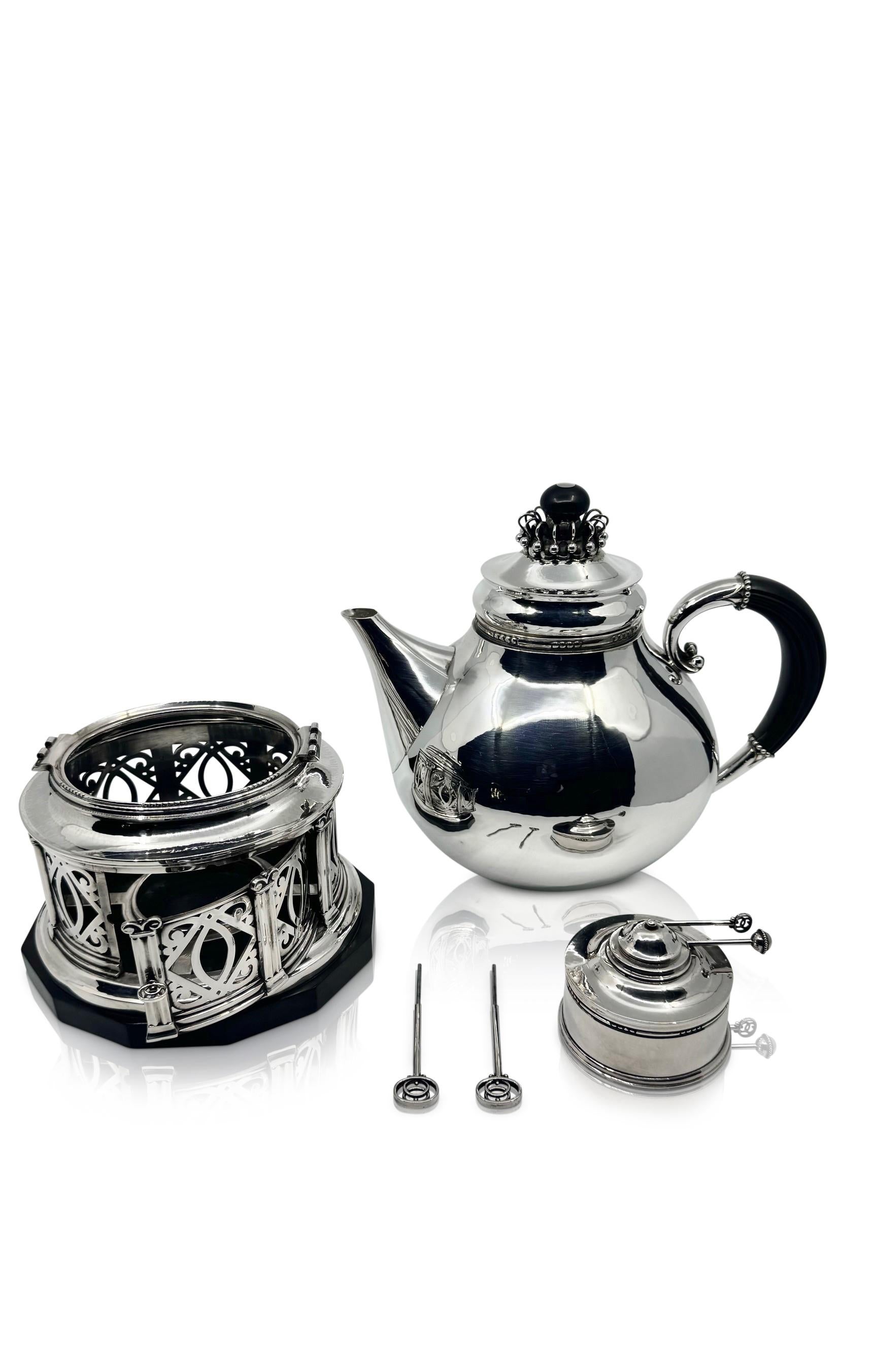 A significant creation from Georg Jensen, this sterling silver hot water kettle or tea machine, bears the distinctive design #251 by Johan Rohde dating back to 1920. The sizable oval vessel features hand-hammered detailing on both the pot and spout.
