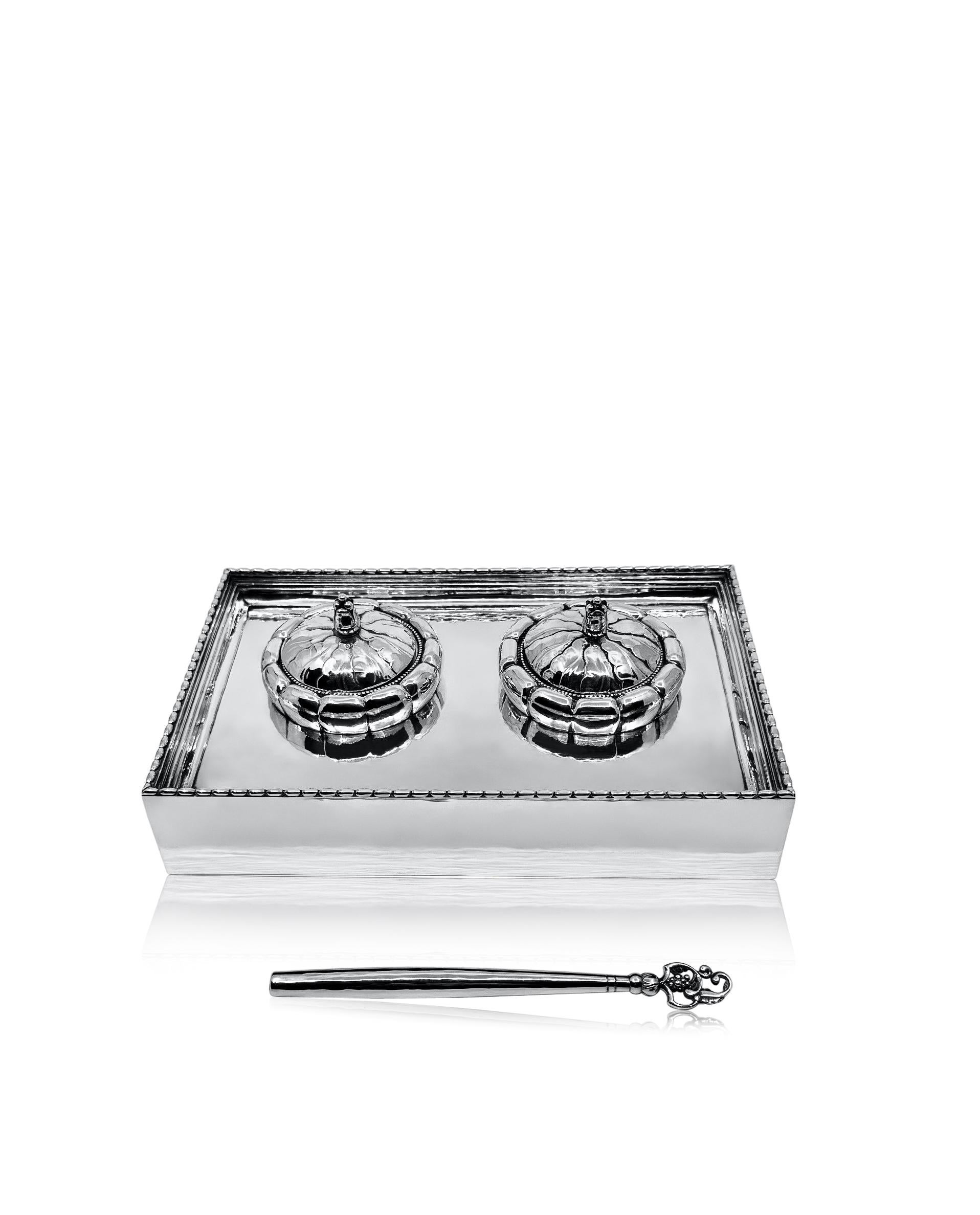 An antique Georg Jensen sterling silver inkwell and matching pen, design #254 by Georg Jensen in 1918. The rectangular base is meticulously hand-hammered, showcasing a finely crafted beaded edge. The inkwell displays intricate hand chasing, with two