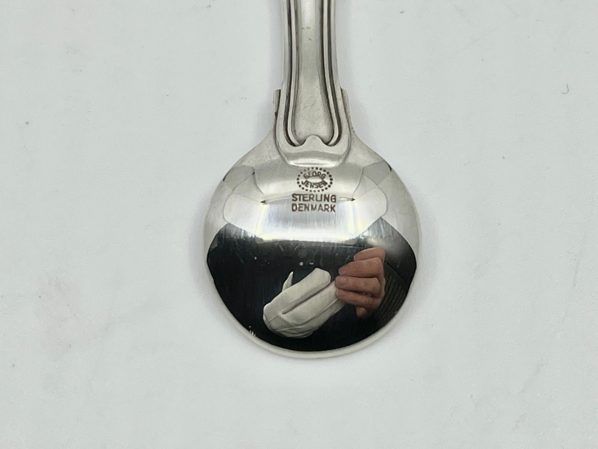 A sterling silver Georg Jensen salt spoon, item #103 in the Old Danish pattern, design #100 by Harald Nielsen from 1947.

Additional information:
Material: Sterling silver
Styles: Art Deco
Hallmarks: With Georg Jensen hallmark, made in