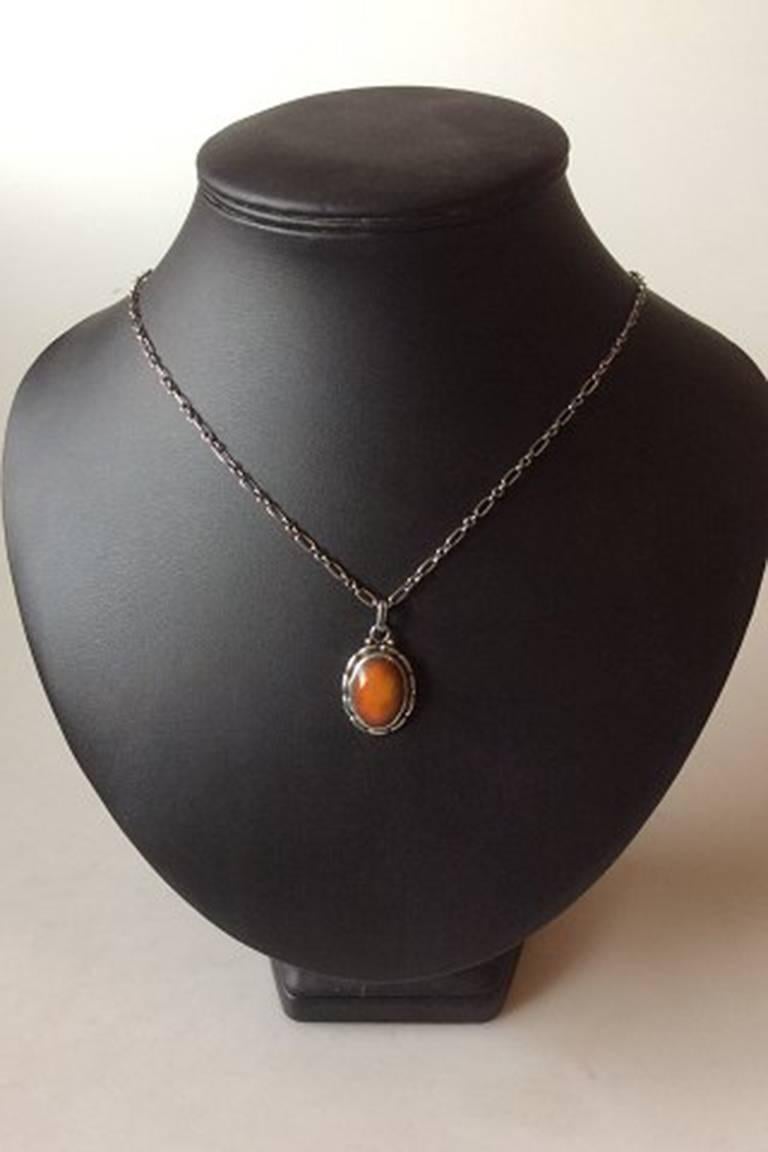 Georg Jensen Sterling Silver Pendant with Amber. Measures 2.5 cm / 1 in. and chain is 50 cm / 19 11/16 in.
Weight is 8.83 g / 0.31 oz.
