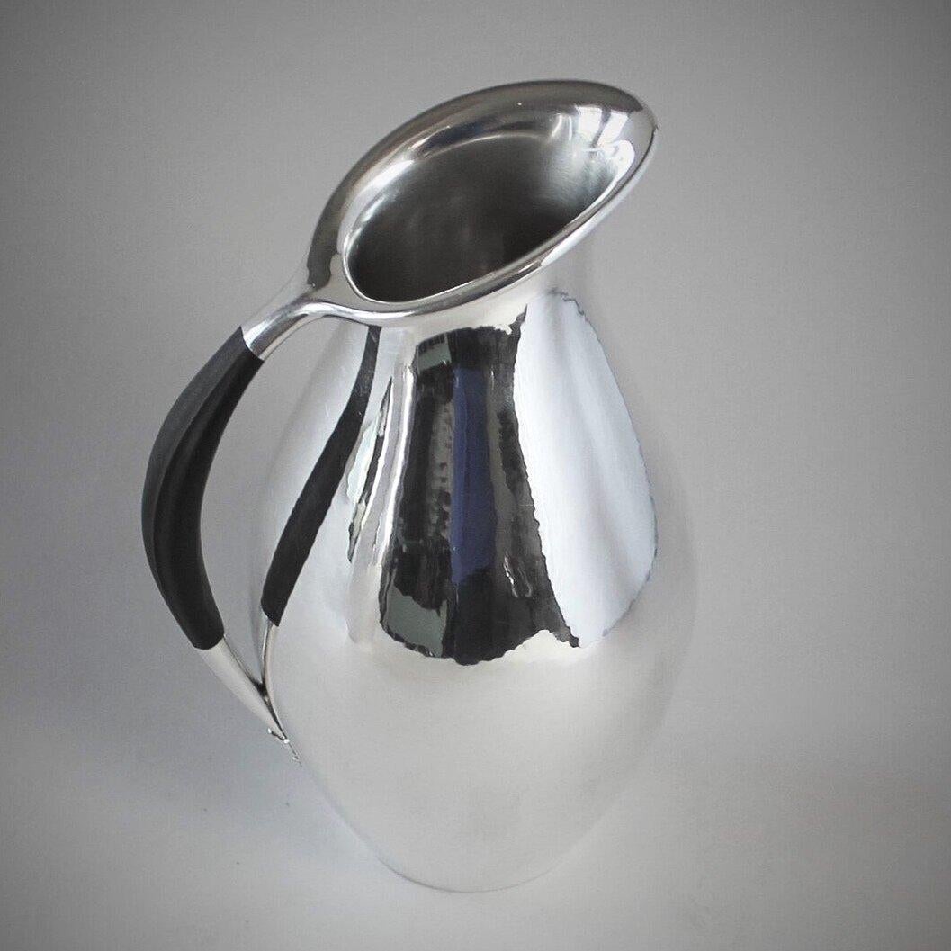 Georg Jensen sterling silver pitcher with ebony handle, No.432E by Johan Rohde.

The Ebony handle was considered a contrasting element and also allows the pitcher to be used for hot water or milk.

We also have the larger size 432F ( shown in