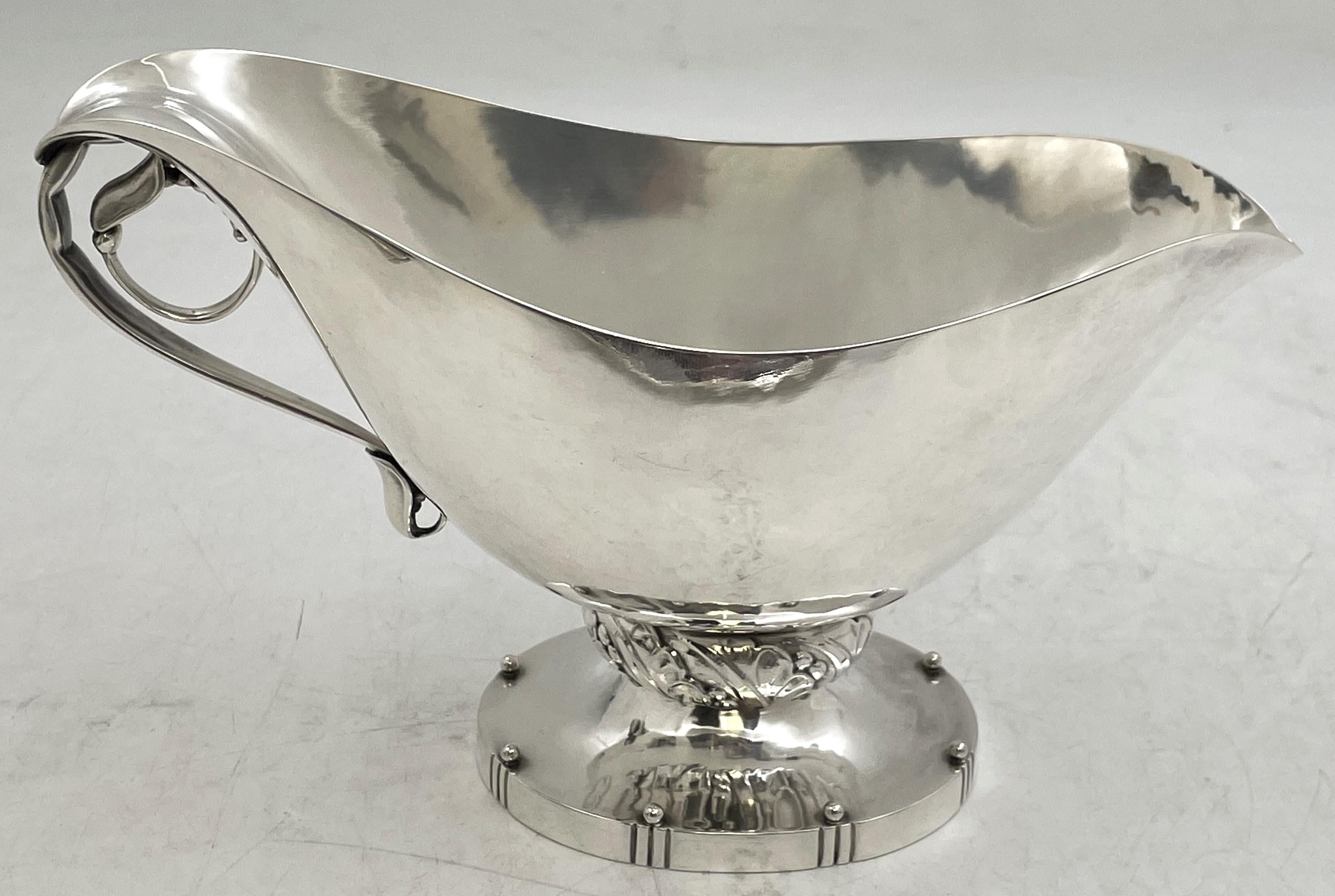 Fuente o salsera Georg Jensen de plata de ley martillada a mano, modelo Blossom número 177, de la década de 1910 o 1920, con el asa y la base adornadas con estilizados motivos geométricos y naturales. Mide 4 7/8'' de alto por 8'' de fondo y 3 7/8''