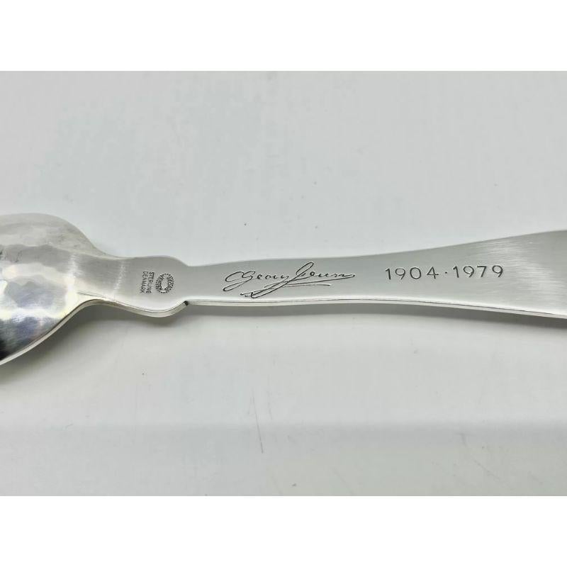 A sterling silver Georg Jensen child’s spoon, set with a small carnelian. This design was made for the 75th Anniversary of Georg Jensen Silversmithy in 1979. Engraved on the back with a Georg Jensen signature and “1904-1979”.

Additional