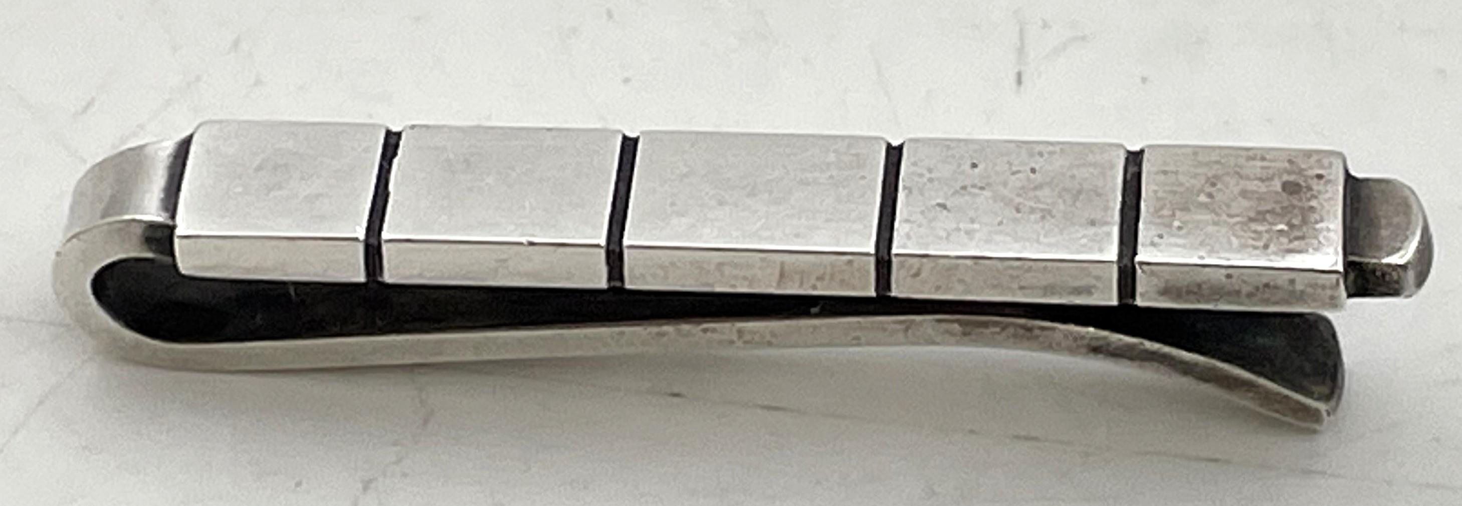 Spilla per cravatta in argento sterling di Georg Jensen, modello numero 64B, con un elegante disegno geometrico. Misura 1 1/2'' di lunghezza per 1/8'' di larghezza per 1/3'' e reca i marchi come mostrato.

L'argentiere danese Georg Jensen