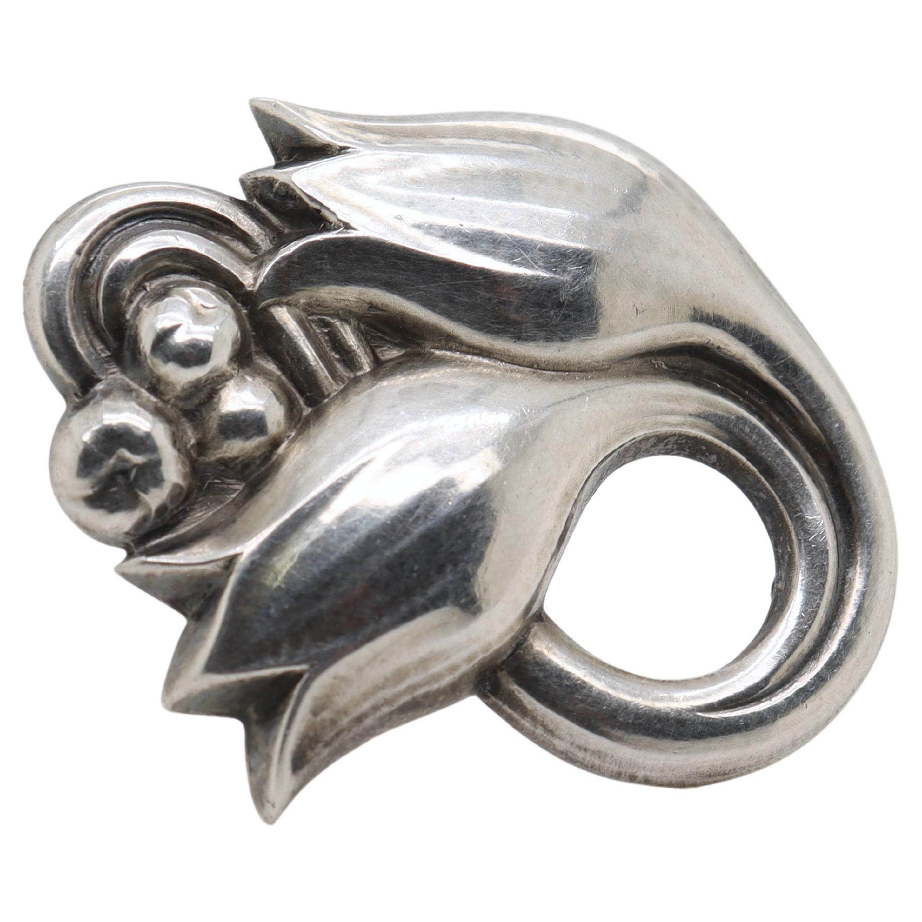 A fine Georg Jensen sterling silver pin or brooch.

Model no. 100A.

Designed by Georg Jensen.

In the form of a hand-hammered, stylized Tulip flowers and berries.

Simply a wonderful brooch from Denmark's premier silversmiths!

Date:
20th Century,