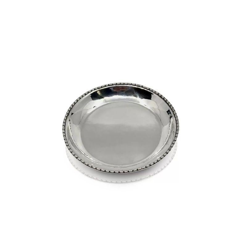 An early silver Georg Jensen circular wine coaster, design #209 by Georg Jensen from 1916. An understated handcrafted design with a slight hammered surface, the side is slightly raised and has a pearled edge. This very early coaster is the wide