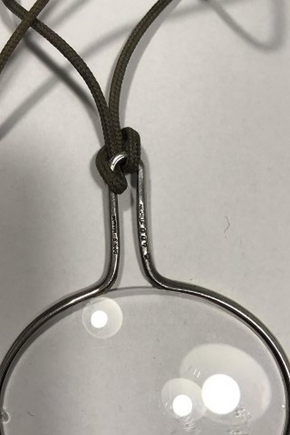 Georg Jensen String mit Sterlingsilber-Anhänger Nr. 400 (Lupe) Torun 
Maße 76 cm (30 in) Lupe 6 cm x 4,8 cm (2 23/64 in 1 57/64 in) 
Kombiniertes Gewicht 14,6 gr/ 0,51 oz(Tiny Chip)
Art.Nr.: 439604