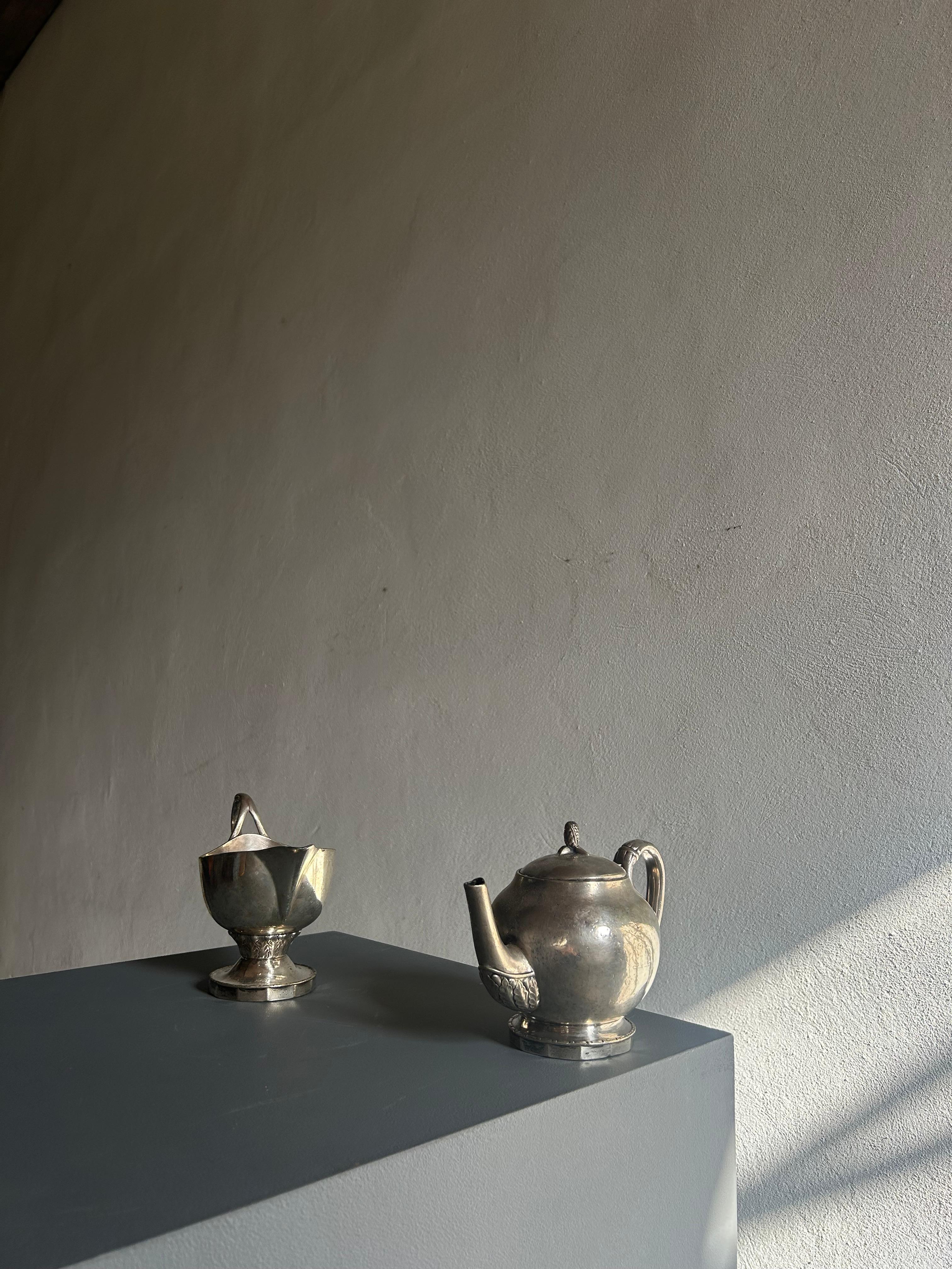 Cet élégant ensemble, composé d'une théière et d'un pot à crème, a été commandé par le célèbre architecte danois Anton Rosen, chargé de concevoir l'emblématique Palads Hotel (aujourd'hui connu sous le nom de Palace Hotel). Ces deux pièces sont