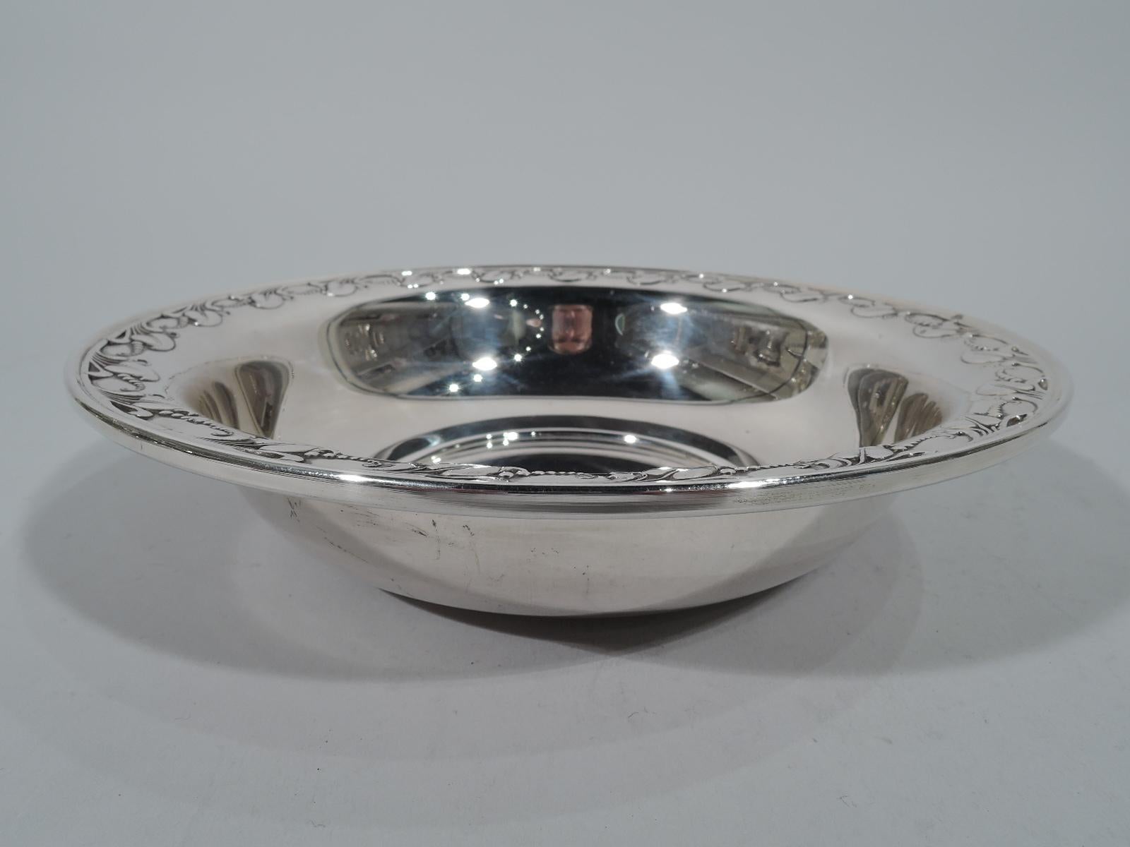 Mid-Century Modern sterling silver bowl. Retailed by Georg Jensen USA Inc. in New York. Circular well, curved sides, and everted rim. Rim decorated with stylized leaves and seeds. A fine harkening back to the Danish source. Hallmark includes no.