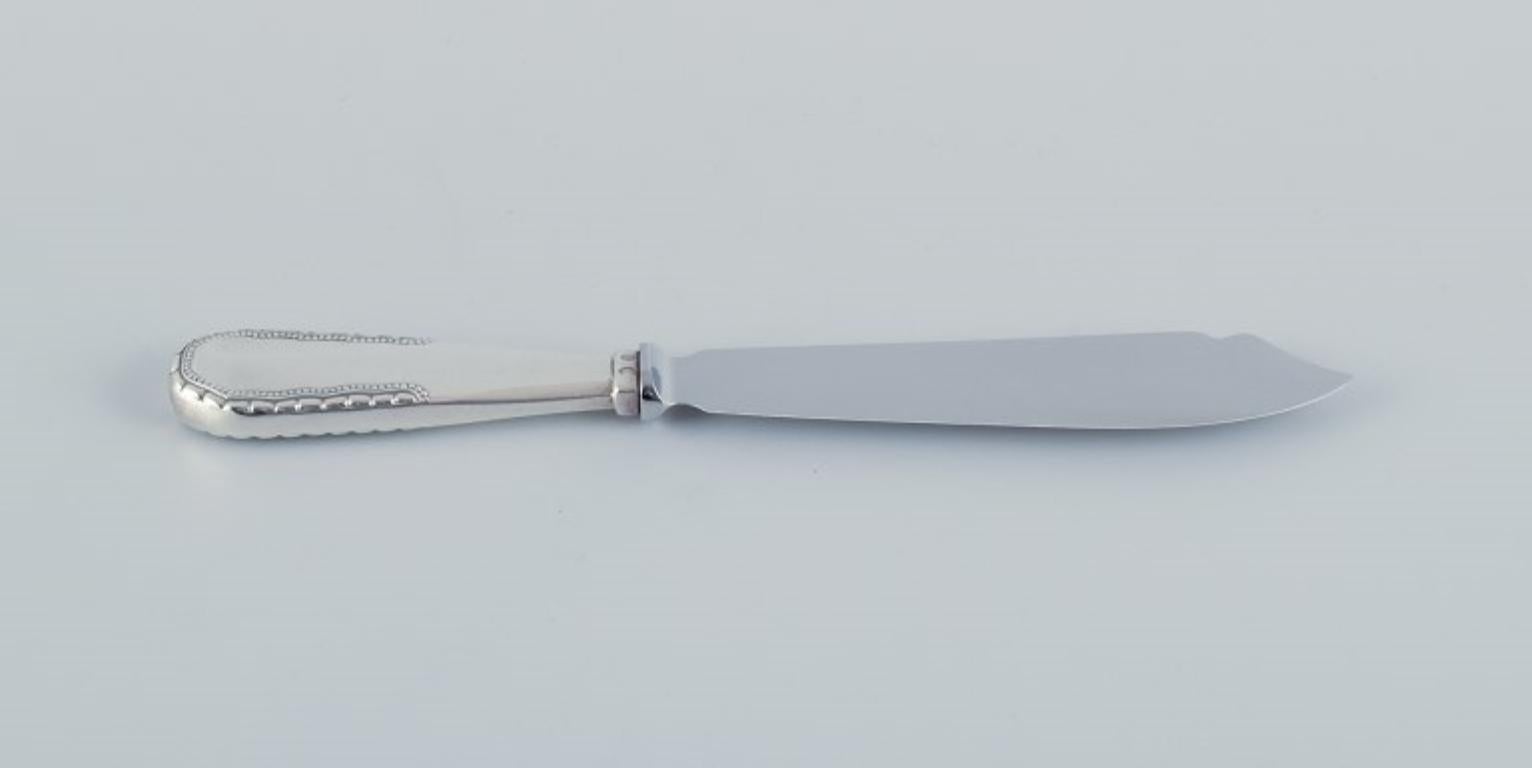 Couteau à gâteau Viking de Georg Jensen en argent 830. 
Lame en acier inoxydable Raadvad.
Poinçon de 1915-1932.
En parfait état.
Dimensions : L 22,3 cm : I.L.A. 22,3 cm.