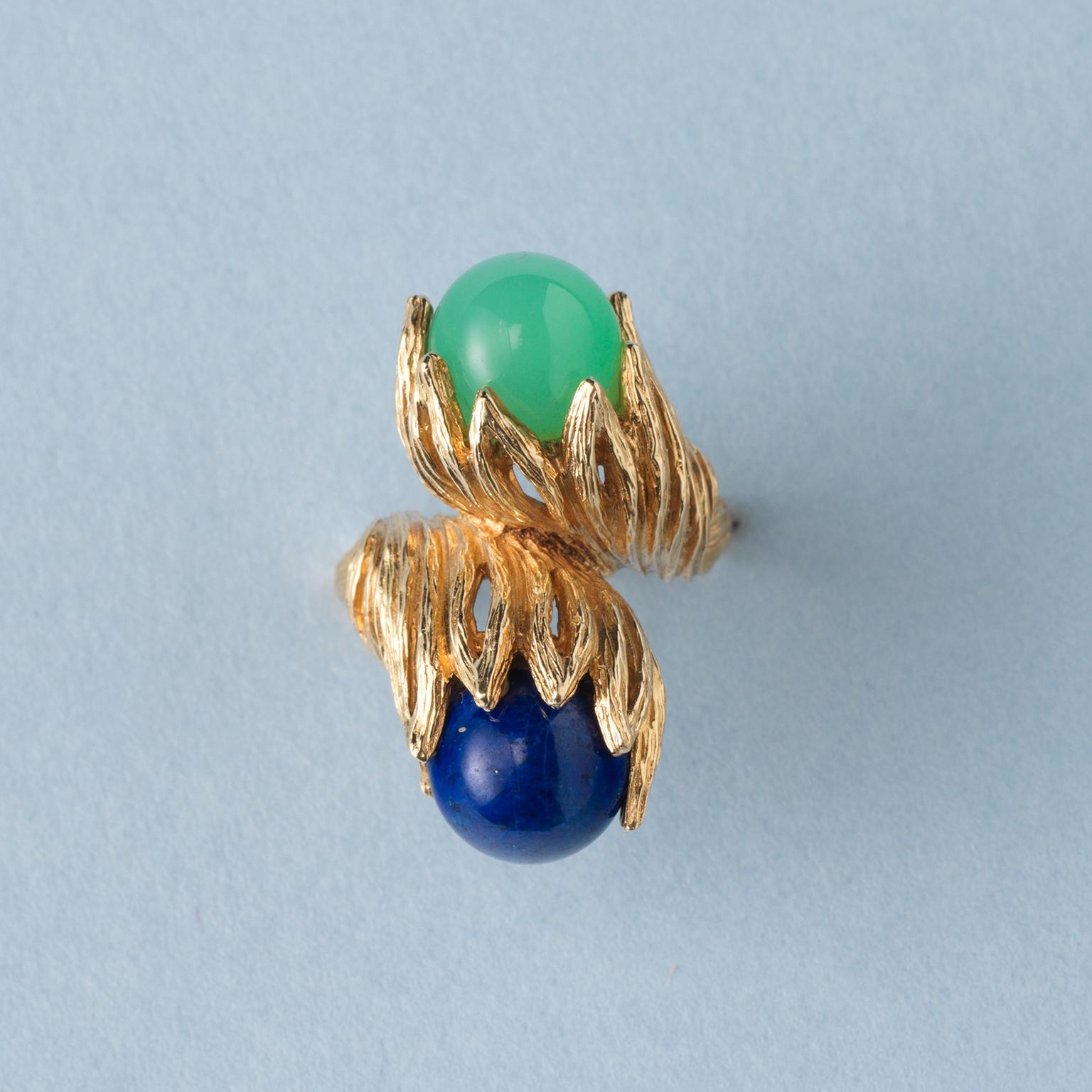 A sculptural 18 carat yellow gold ring with two textured leaves one is holding a lapis ball and one is set with a green calcedony ball, signed: Georg Lauer, Pforzheim, circa 1960-1970.

ring size: 16.5 mm / 6+ US.
weight: 18.13 grams
width: 2.1 – 30