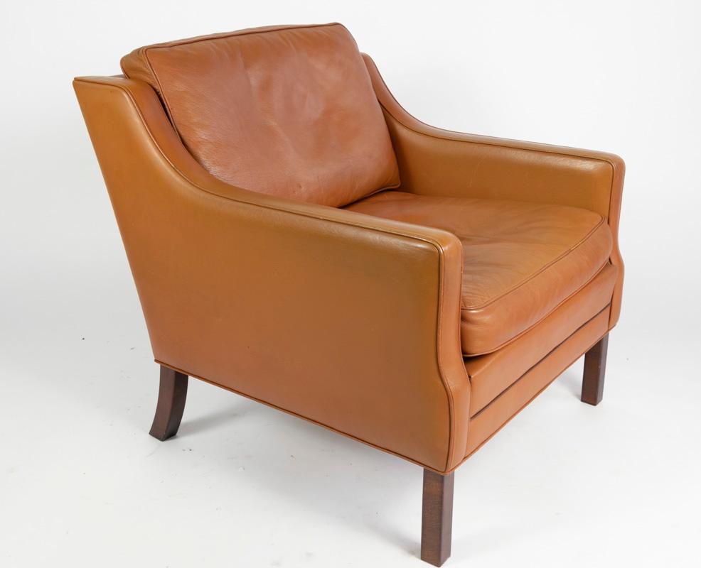 A sophisticated lounge chair by Georg Thams, low back armchair covered in lovely caramel leather.

The build quality is excellent and the leather is very healthy with feather and down filled squabs which are comfortable and inviting.
 