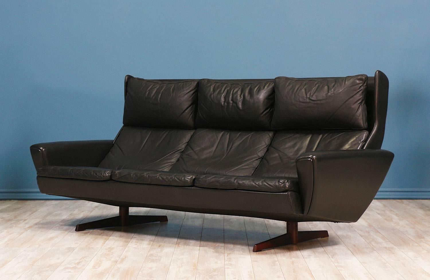 Winged back sofa designed in Denmark by Georg Thams for Vejen Polstermøbelfabrik circa 1970’s. This lovely sofa features newly refinished solid rosewood propeller legs and its original black leather upholstery displaying a beautiful age-appropriate