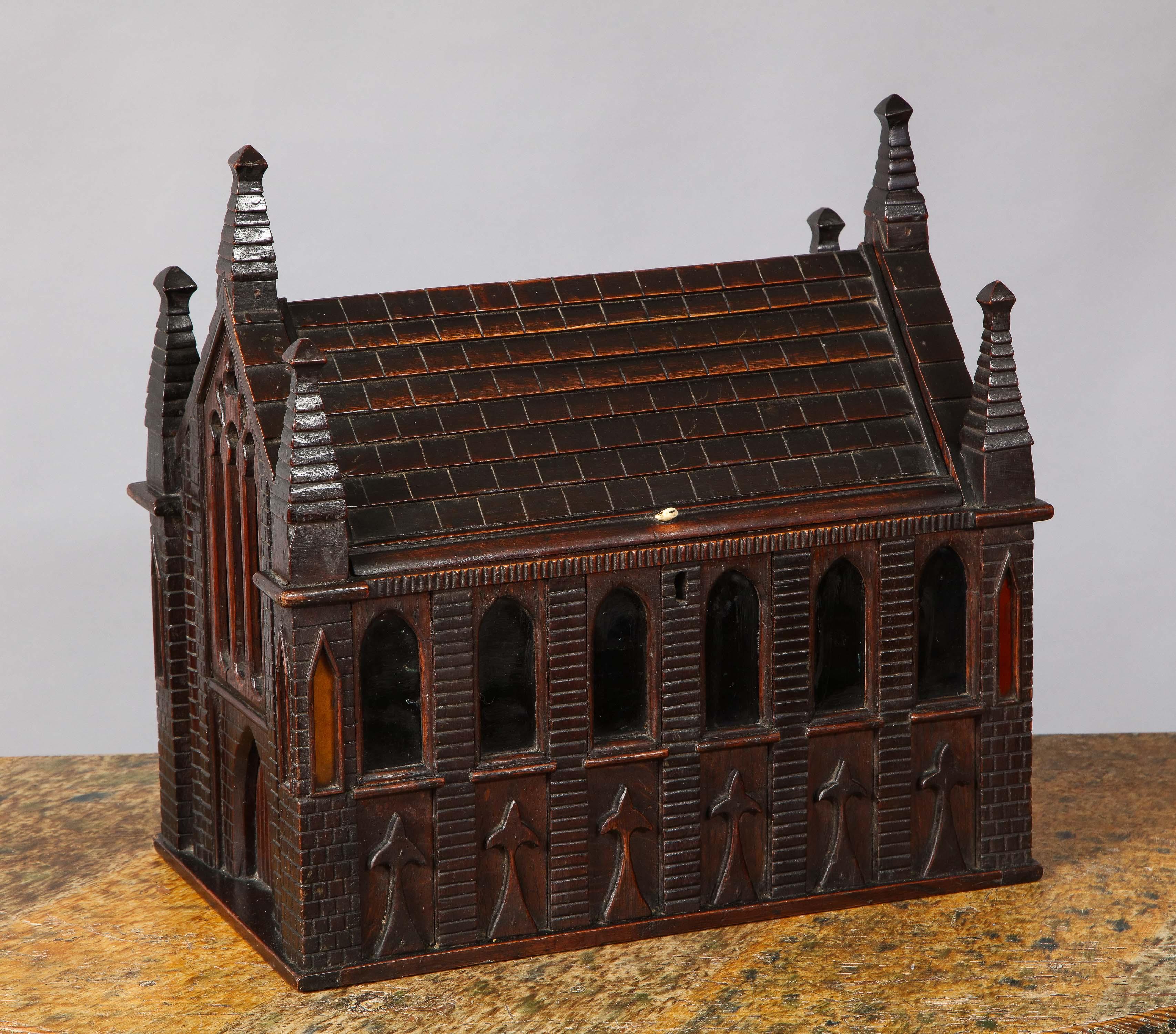 Very fine English early 19th century mahogany architectural model of a church, the multiple steeples flanking a faux carved slate shingled room, which hinges open to reveal felted interior, the walls with applied carved decoration, the whole
