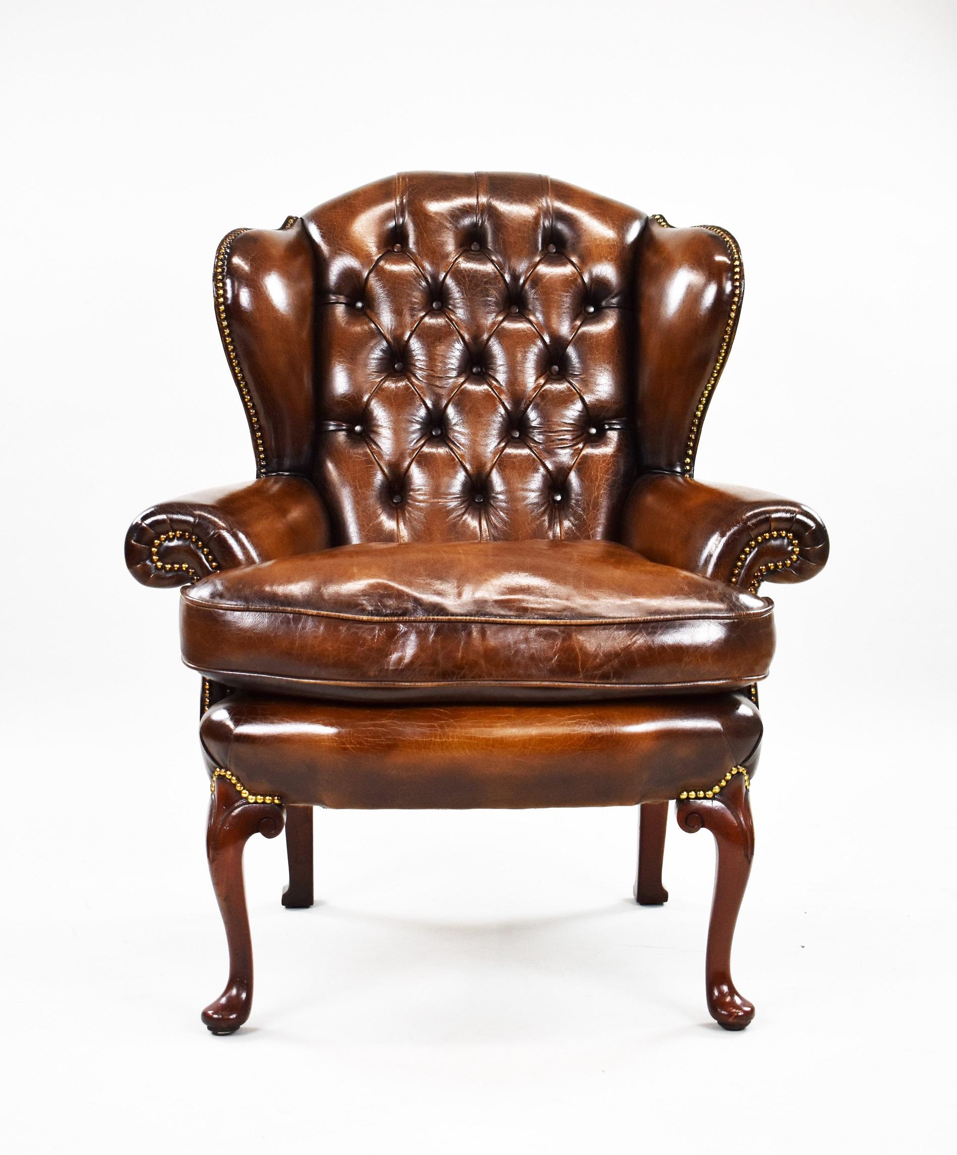 Poltrona in mogano in stile George II, rivestita in pelle marrone tinta a mano, con schienale abbottonato e braccioli a voluta, con borchie sulla parte superiore, sui lati e sui braccioli. Si regge su gambe cabriole.