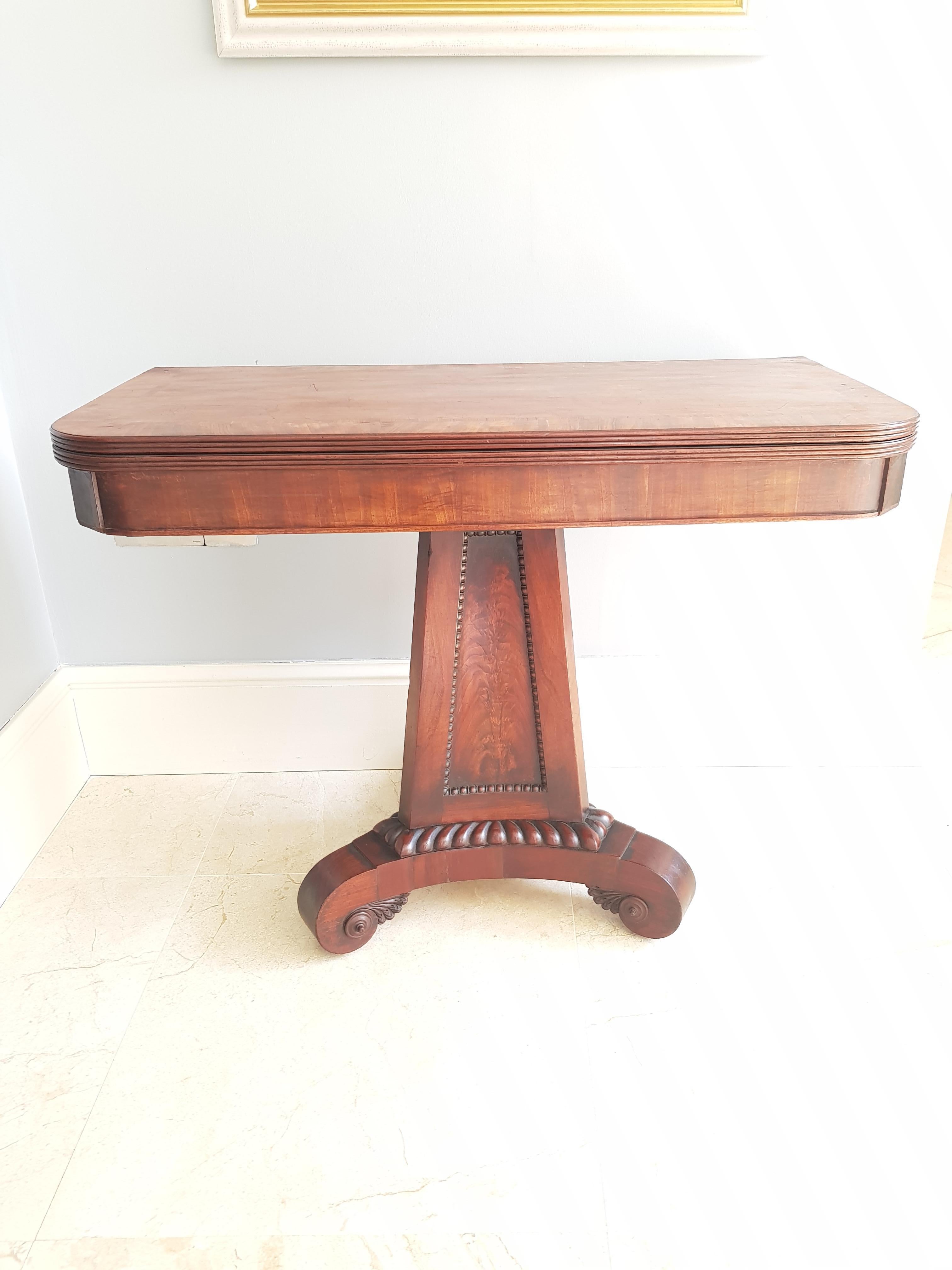 A fine Regency period tea table of Irish or English manufacture in the manner of Thomas Hope. The piece is finely carved with superior crossbanded mahogany leaves over a contained storage compartment, with a finely carved pedestal support and
