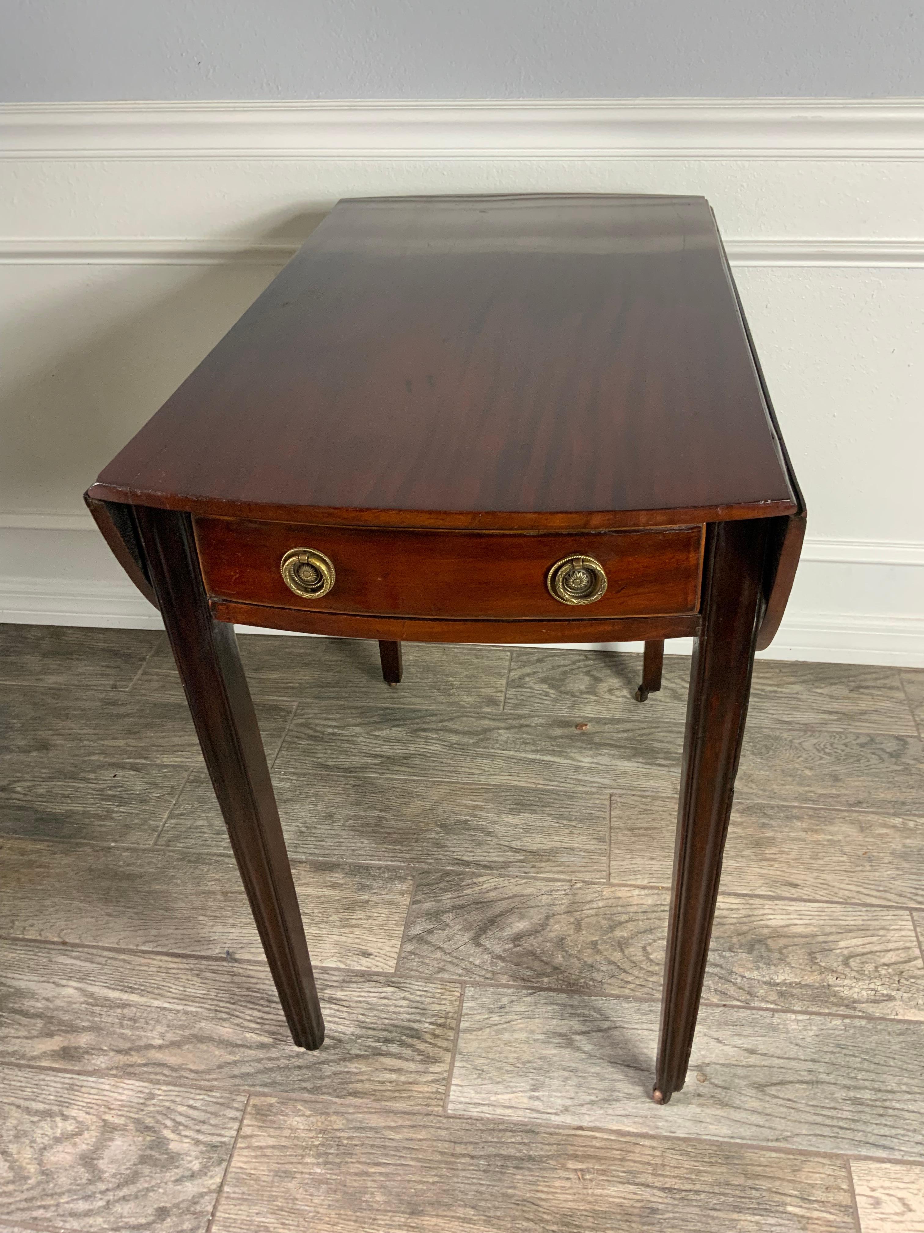 A very attractive 18th century Georgian Mahogany Pembroke table on tapered reeded legs ending on the original wood wheel casters. Excellent color and patina to the old refinished surface. The hinges and drawer hardware are original to the piece.
