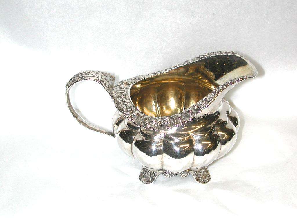 George IV Newcastle silver melon shaped creamer, 1829.
Heavy quality silver melon shaped cream jug with acanthus leaf handle and wonderful
floral border round the top. The 4 feet are decorated with shells and scrolls.
The silversmith is John