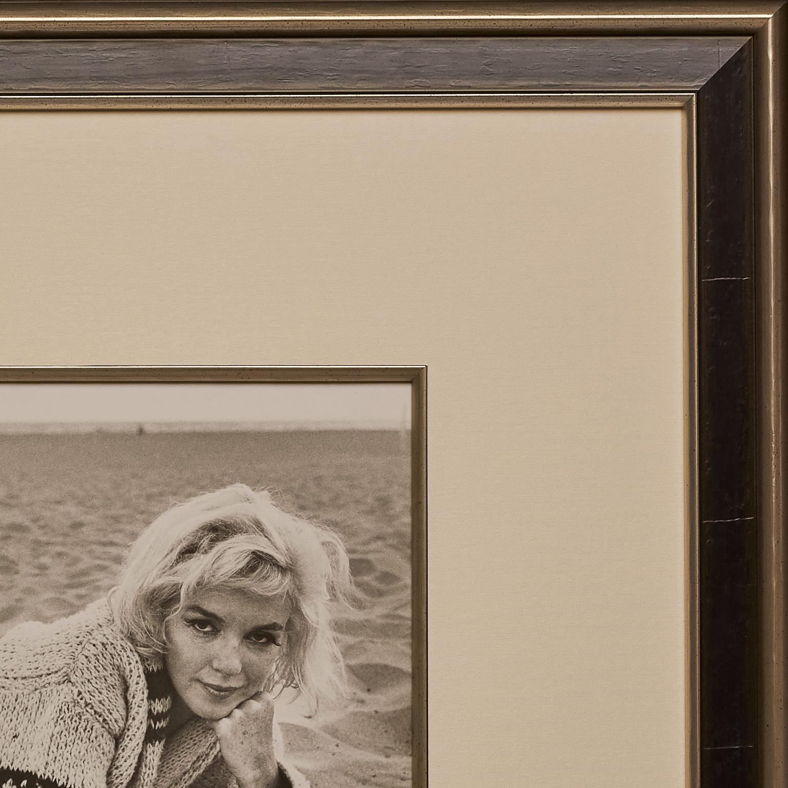 This beautiful black and white silver-gelatin photograph of Marilyn laying in the sand, wrapped up in a woollen sweater, personally belonged to photographer, George Barris. 

It measures 9 5/8 x 7 5/8 inches (24.45 x 19.37cm) and features the