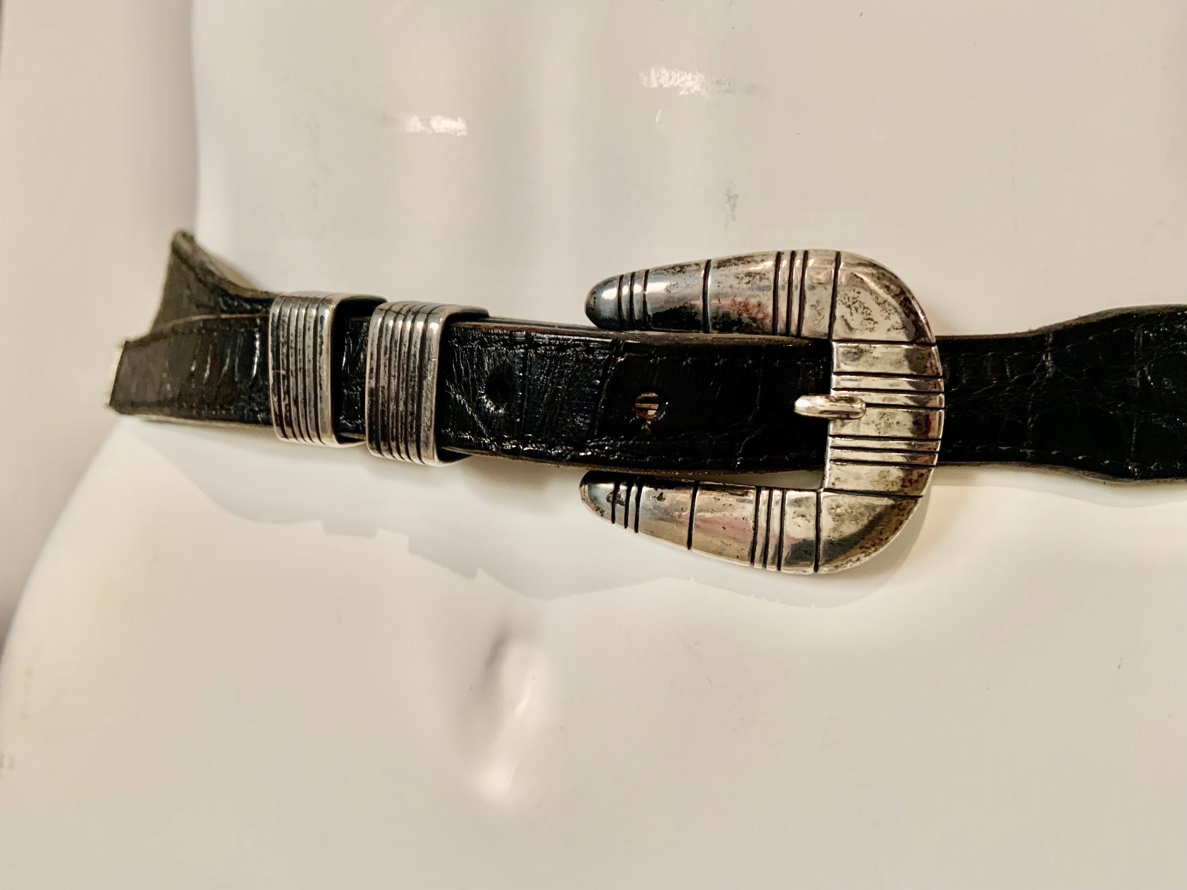 This hand made sterling silver buckle, keeper and tip set made and signed by George Begay has a graphic linear design on all three pieces.  The buckle is stamped Sterling and GB and it is combined with a black leather and stamped crocodile belt. 