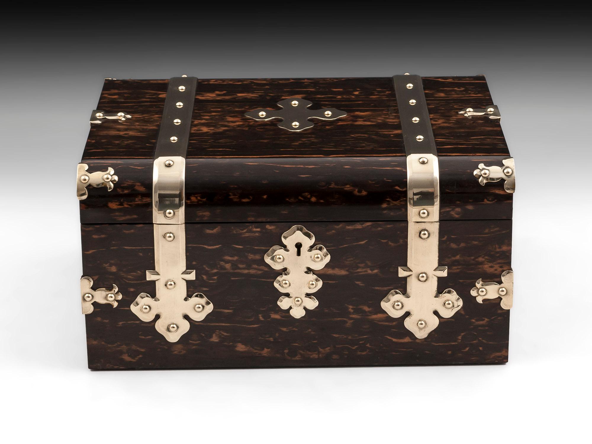 George Betjemann & Son Jewelry box veneered in sumptuous figured Coromandel with ornate applied brass straps running from front to back, with vacant brass initial plate, escutcheon and corner brackets for added strength. 

The interior of this