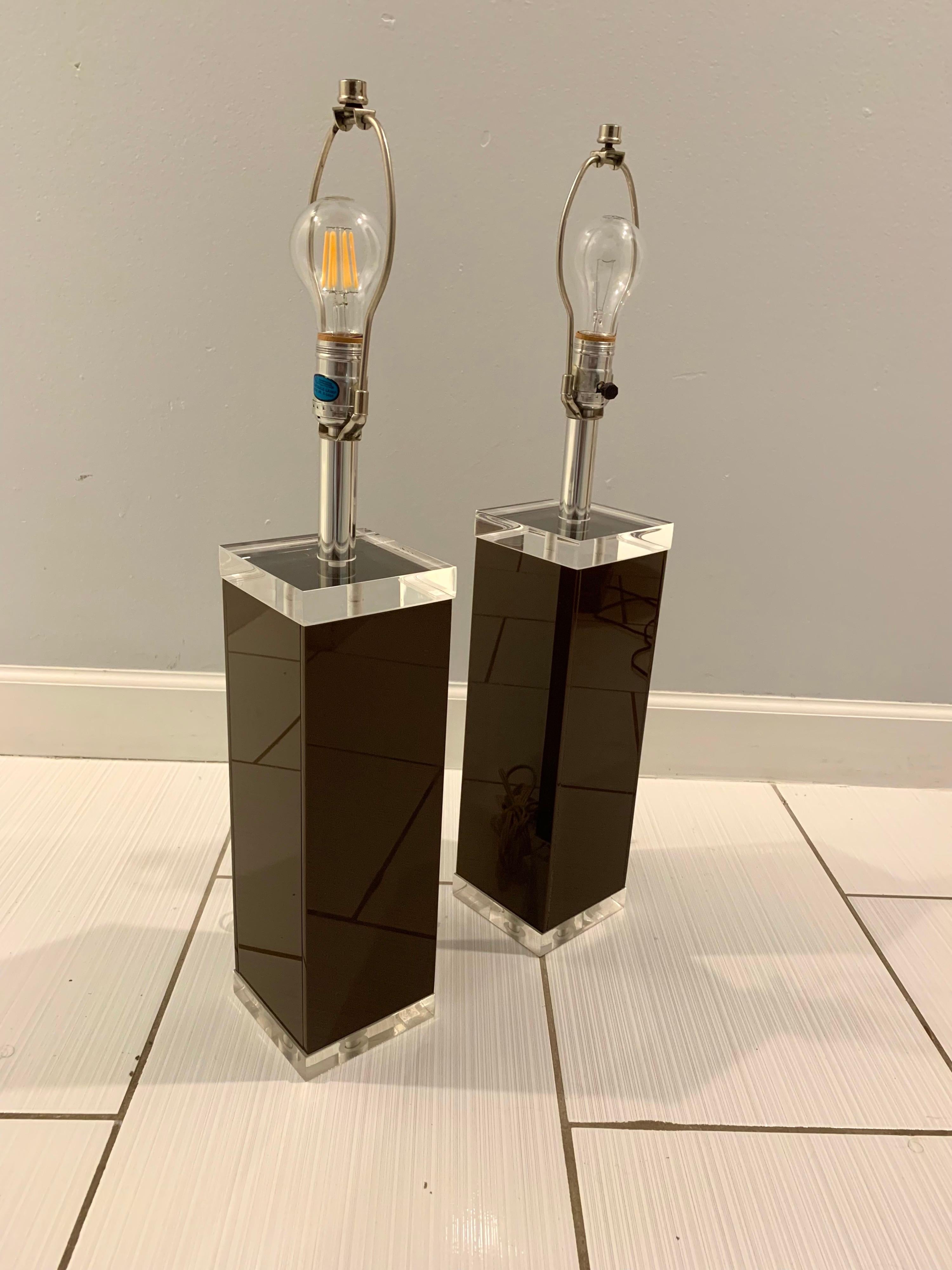 Gorgeous pair of lucite lamps designed and hand crafted by George Bullio. Dark rich chocolate colored lucite framed on top and bottom with crystal clear lucite blocks. Chrome stand to hold the bulb and shade. Refined and clean look. Would fit well