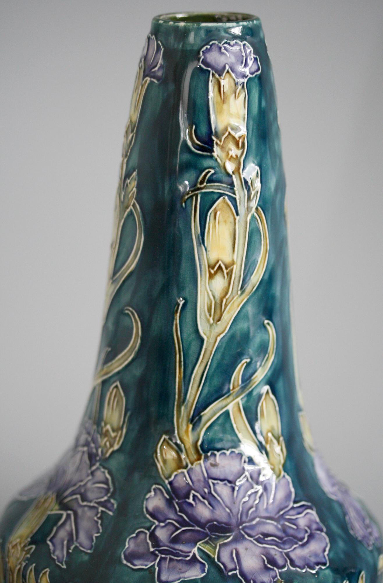 A stunning and scarce iconic early Art Deco Hancock & Sons Morrisware hand painted art pottery vase with flowering carnations by George Cartlidge dating between 1918 and 1926. This stylish flask shaped vase stands on a narrow rounded base with a