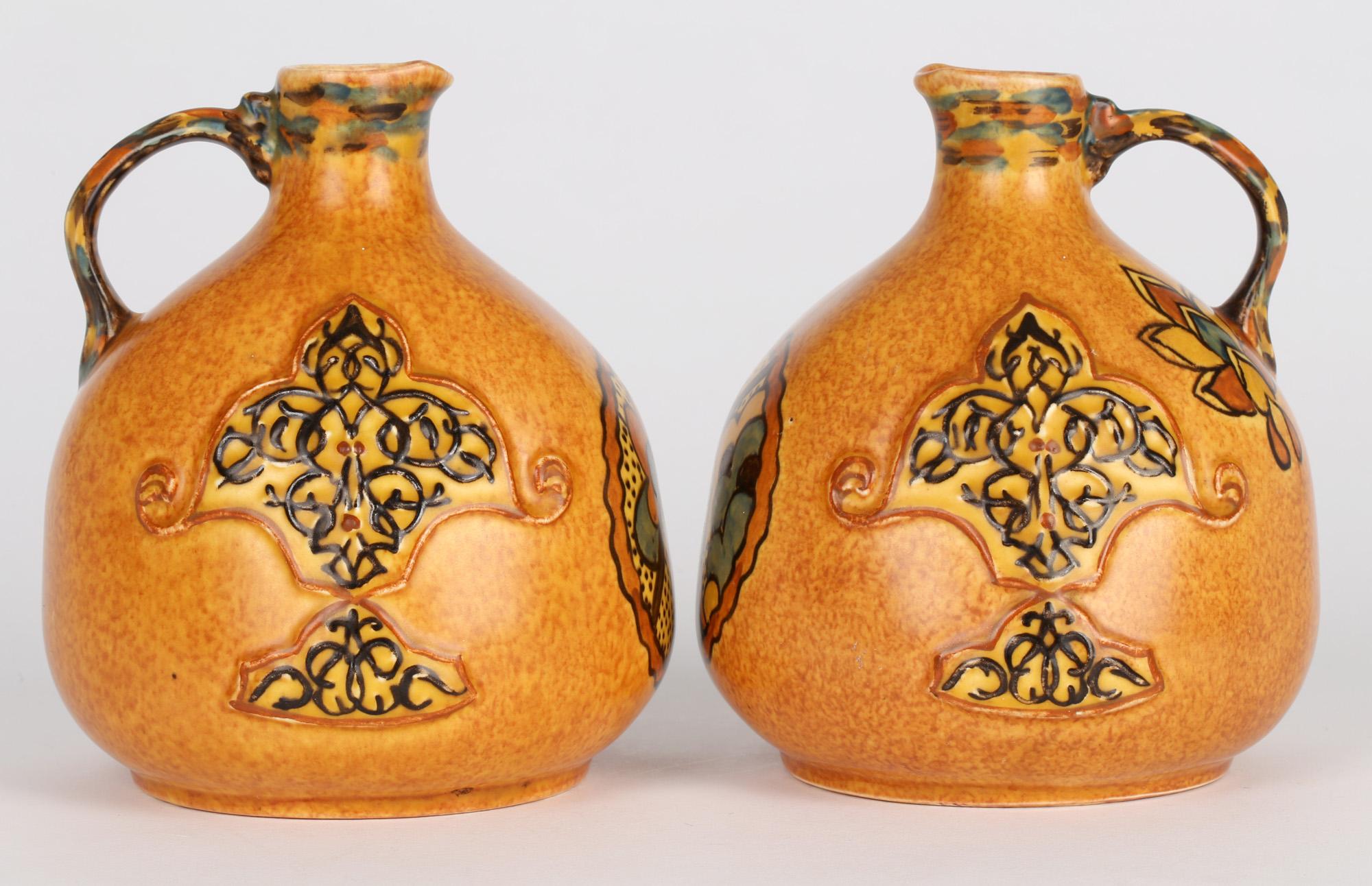 A very stylish pair Art Deco George Clews & Co, Tunstall, Chameleon Ware reproduction of Persian Art handled pottery jugs dating from around 1930. The jugs stand on a rounded base and have a slightly compressed rounded shape body with a narrow short