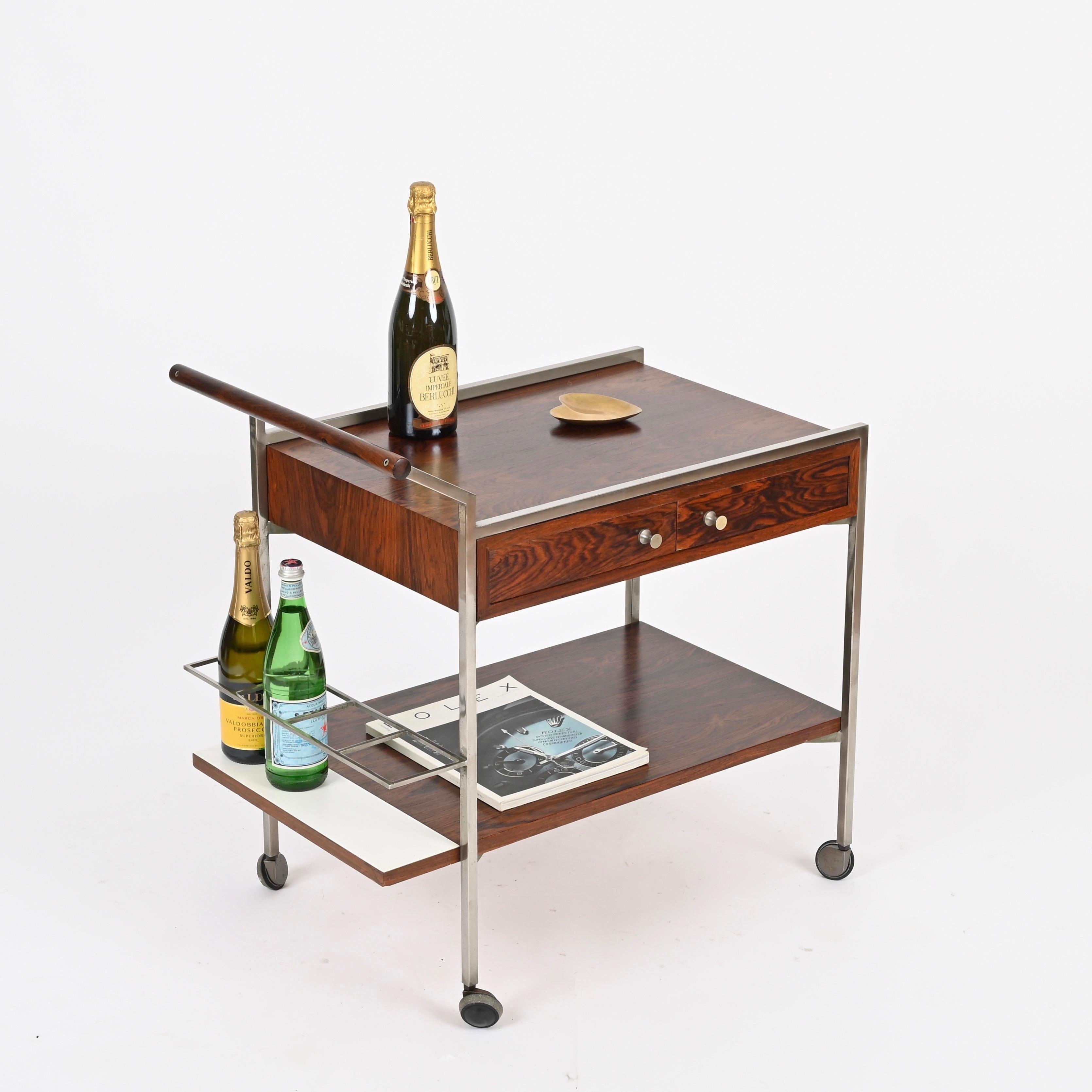 Splendido carrello da bar italiano del Mid-Century, interamente realizzato in legno di palissandro, metallo cromato e laminato bianco. Questo pezzo incredibilmente elegante e unico è stato disegnato da George Coslin e prodotto in Italia negli anni