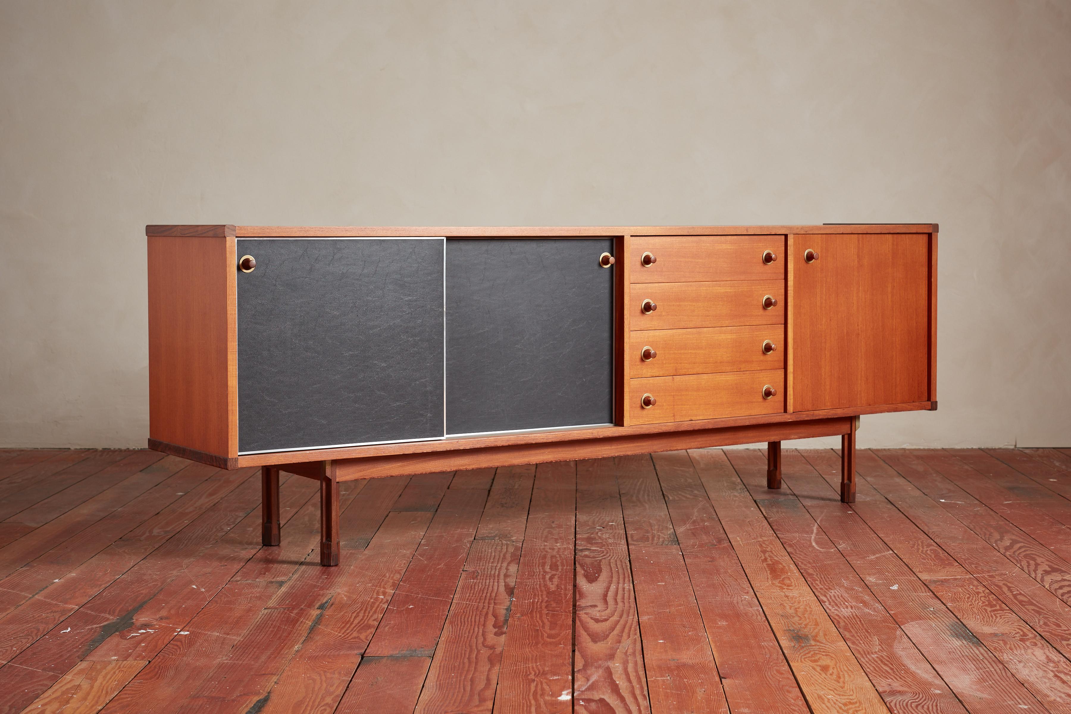 Merveilleux buffet en teck conçu par George Coslin - Italie, années 1960

Le meuble comporte deux portes coulissantes en similicuir noir avec des étagères de rangement et quatre tiroirs centraux avec des boutons en bois sculpté avec des détails en