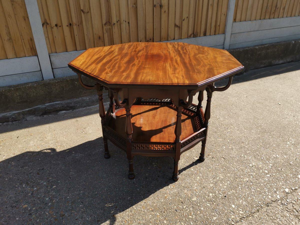 George Faulkner Armitage. An Anglo-Japanese octagonal mahogany center table, with eight curved supports and shaped apron with subtle carved details on eight turned baluster legs united by a lower shelf with fretwork details above.
Original label