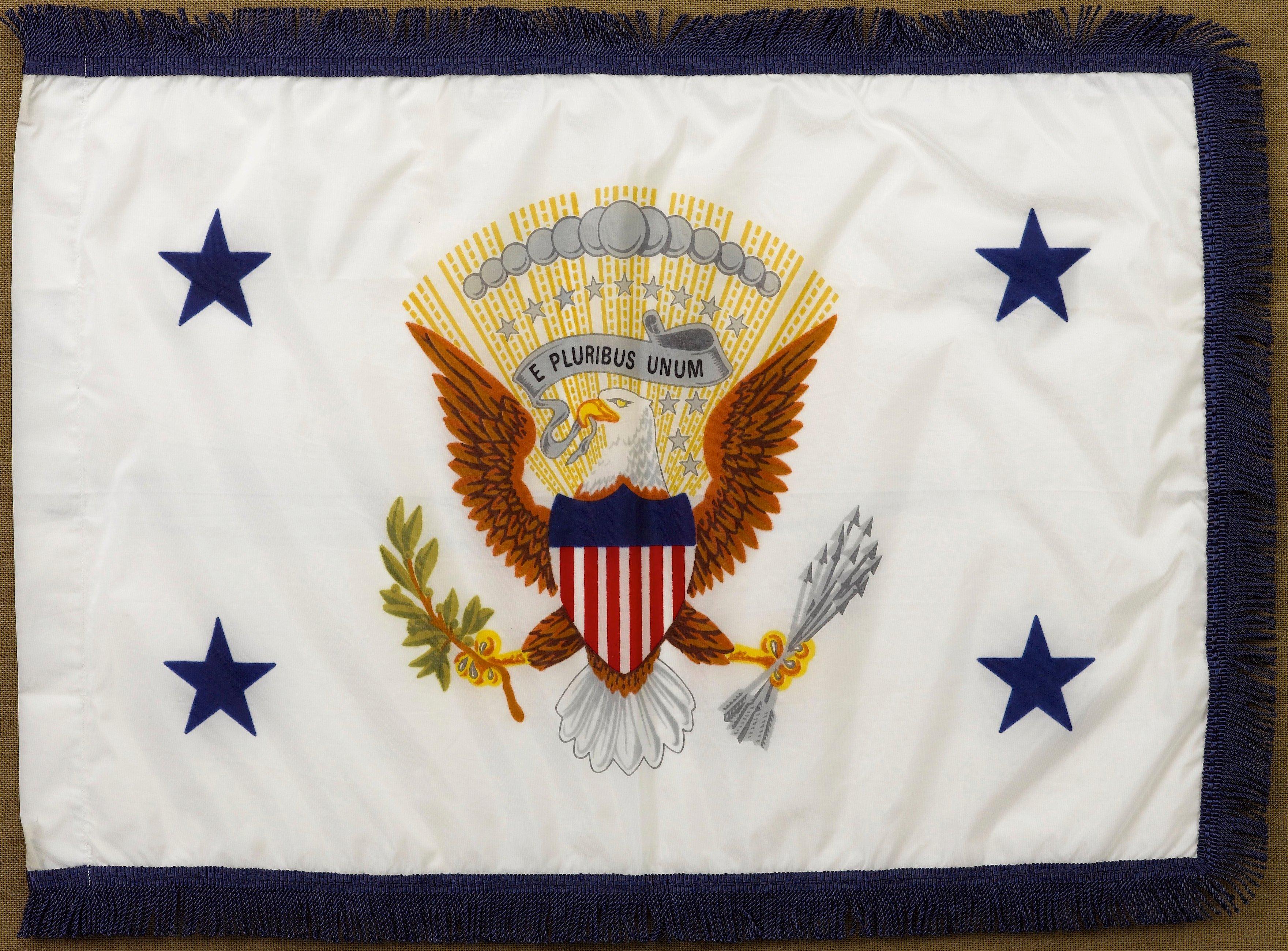 This is an original Vice Presidential limousine flag, flown when George H. W. Bush was Vice President.

This white limousine flag has the Presidential Seal at center and blue five-pointed stars in each of the four corners. The flag has a blue