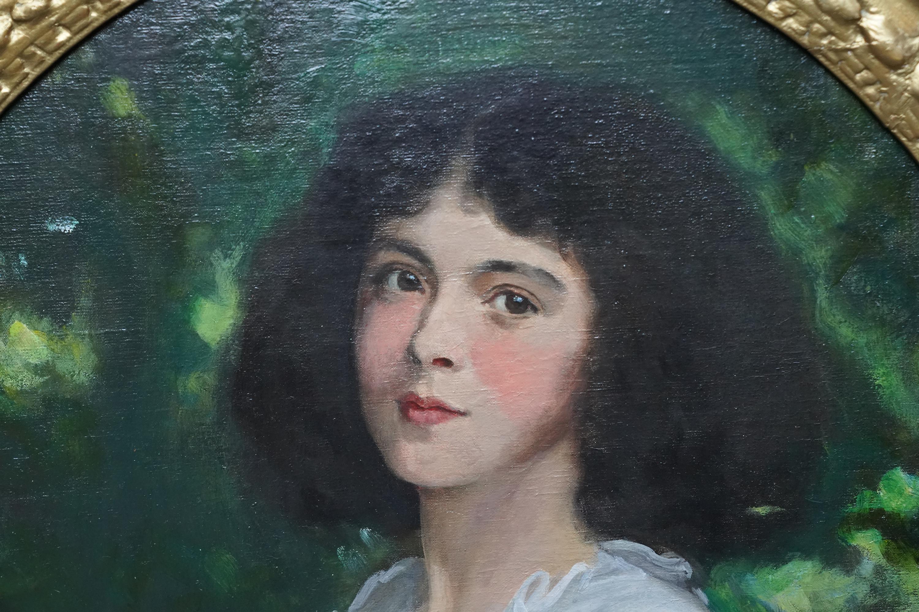 Dieses schöne schottische Ölgemälde mit ovalem Porträt aus der Edwardianischen Zeit stammt von dem bekannten Künstler George Harcourt. Es wurde um 1910 gemalt und zeigt ein stehendes Porträt eines jungen Mädchens in Dreiviertellänge mit dem Grün der