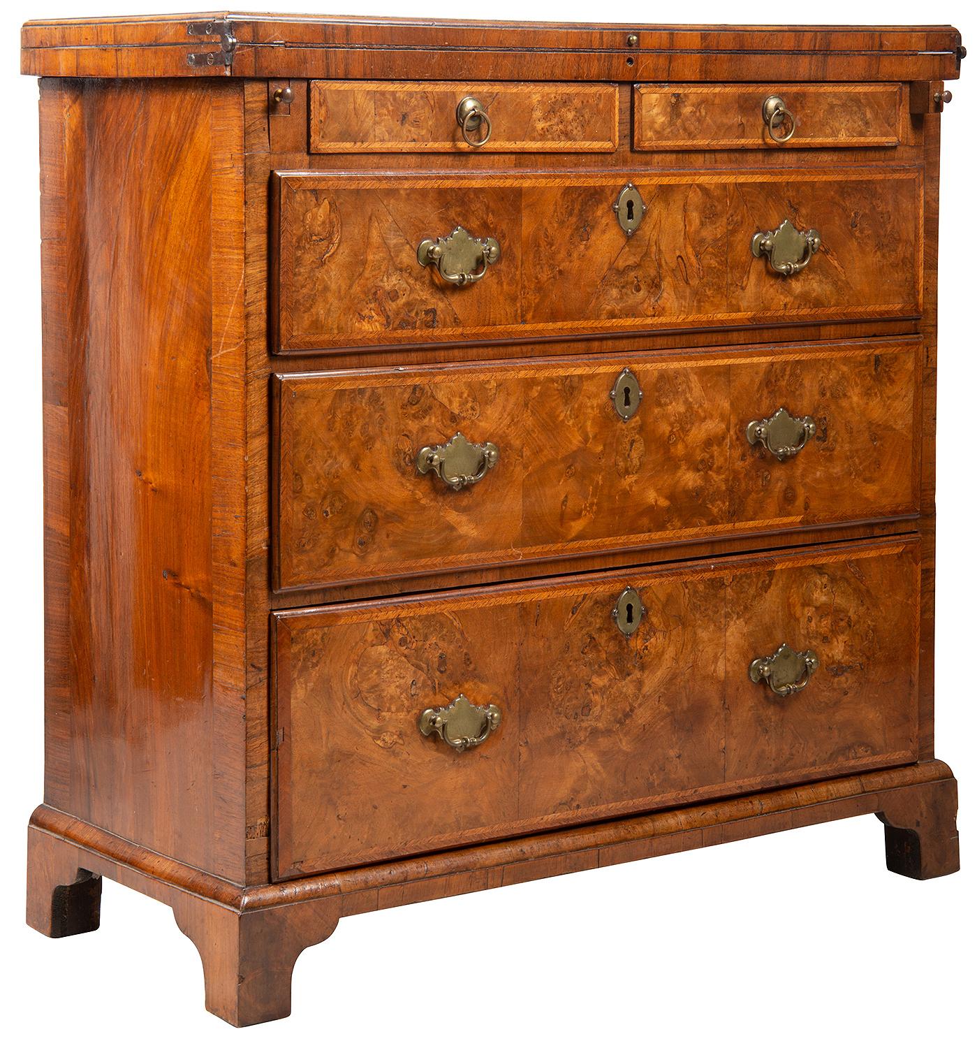 A superb George I figured walnut and feather banded fold over top bachelor chest. The rectangular top with fine figured veneers and crossbanded. Double drawers to the top, a barer either side to support the hinged top which has an inset leather top.