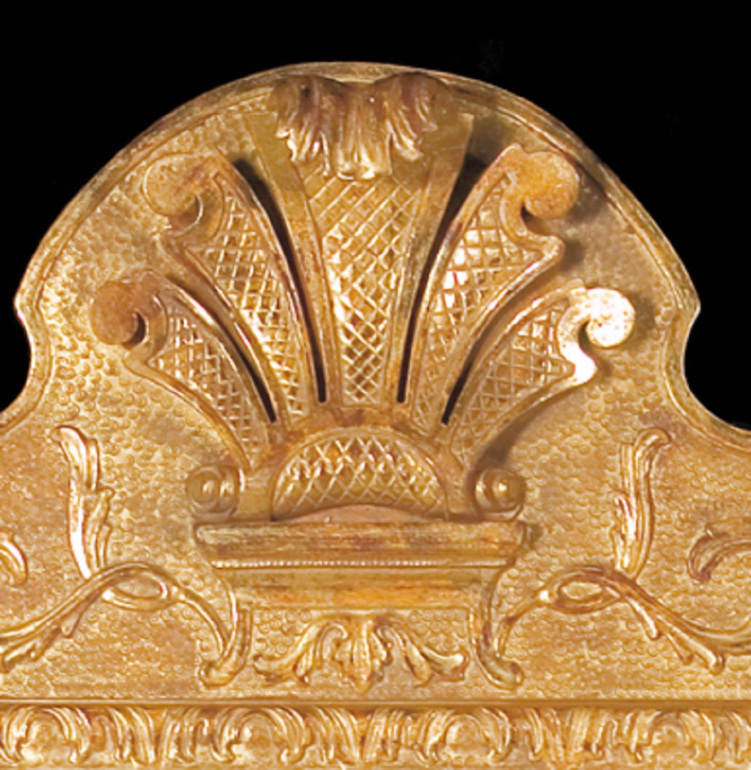 Un miroir de style George I en bois doré sculpté et en gesso. La plaque de miroir se trouve dans un cadre moulé sculpté de feuilles et de coquilles, sous une crête façonnée centrée par une plume percée, sur un socle moulé. Le cadre texturé est