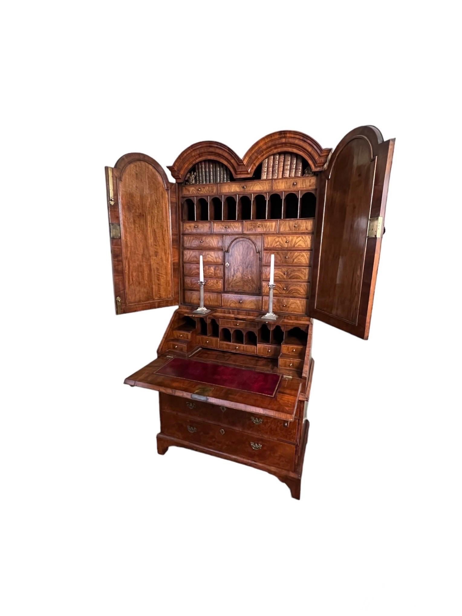 Libreria da ufficio in radica di noce intarsiata di Giorgio I, 1720 circa, con doppia funzione. 
In due parti con una doppia cornice modanata ad arco sopra una coppia di porte modanate ad arco che racchiudono una disposizione di  cassetti e