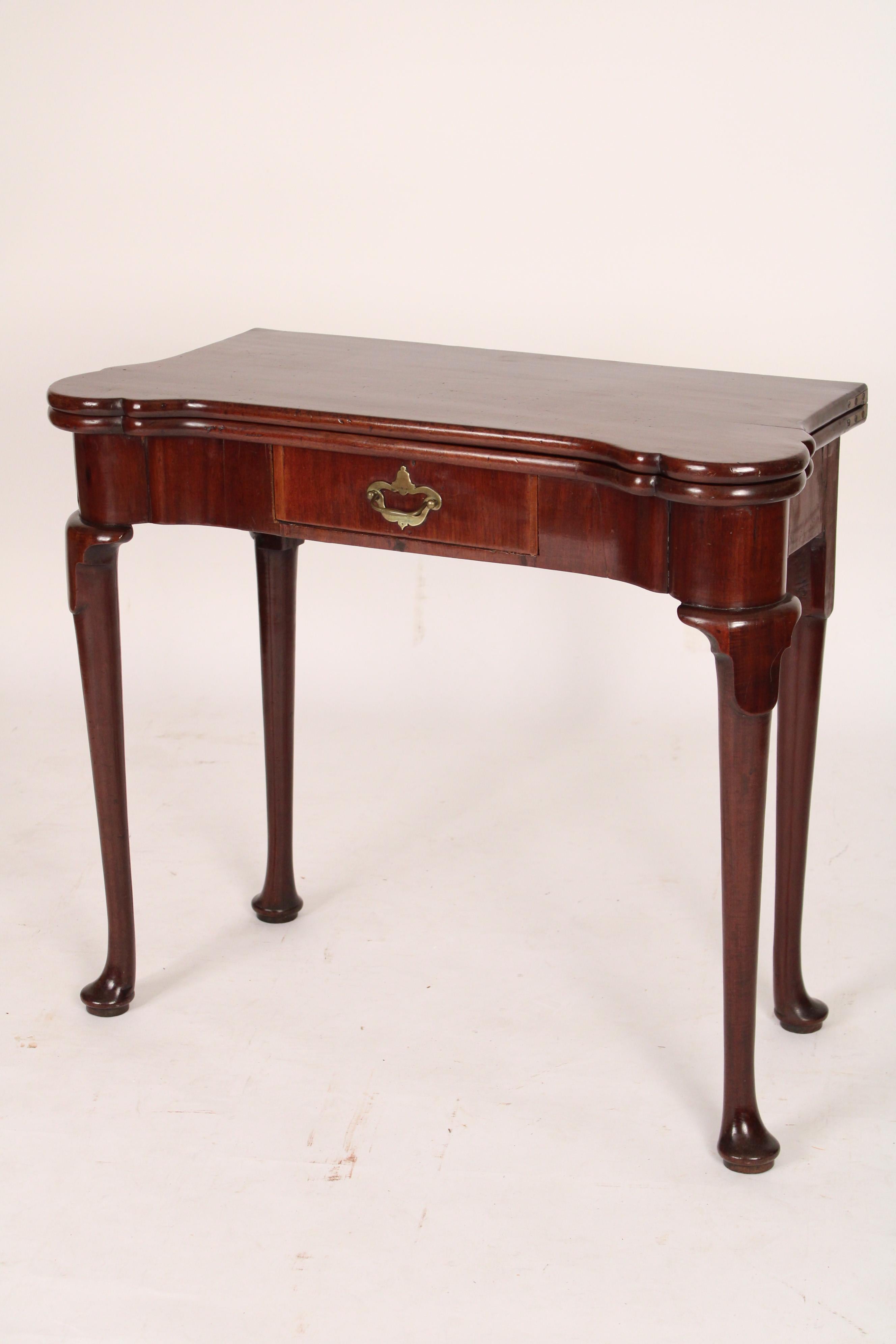 George I mahogany games table, 18th century. With a rectangular over hanging top with turret corners, a frieze drawer, cabriole legs ending in pad feet. The back left leg swings out to support the top when the top is opened.